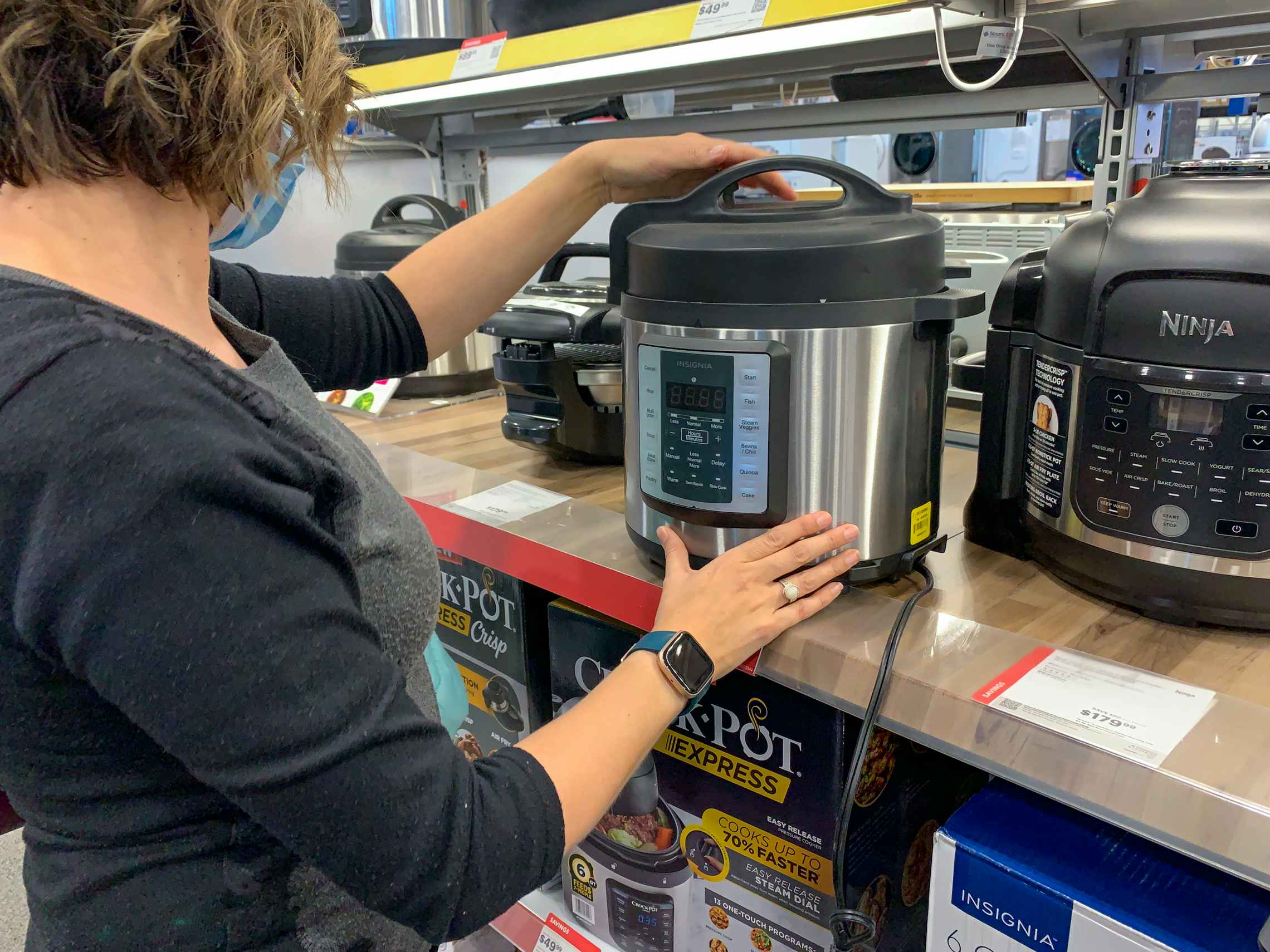 A woman looking at a pressure cooker at Best Buy