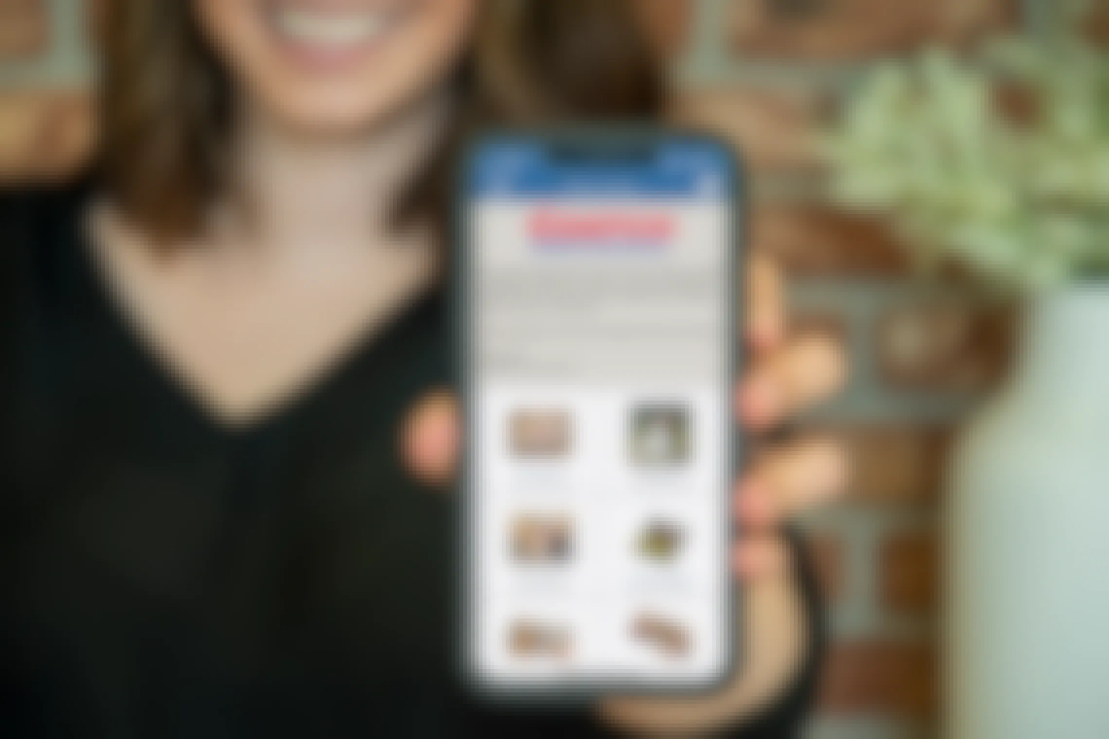 A woman holding a cell phone out, with the Costco photo center app on it