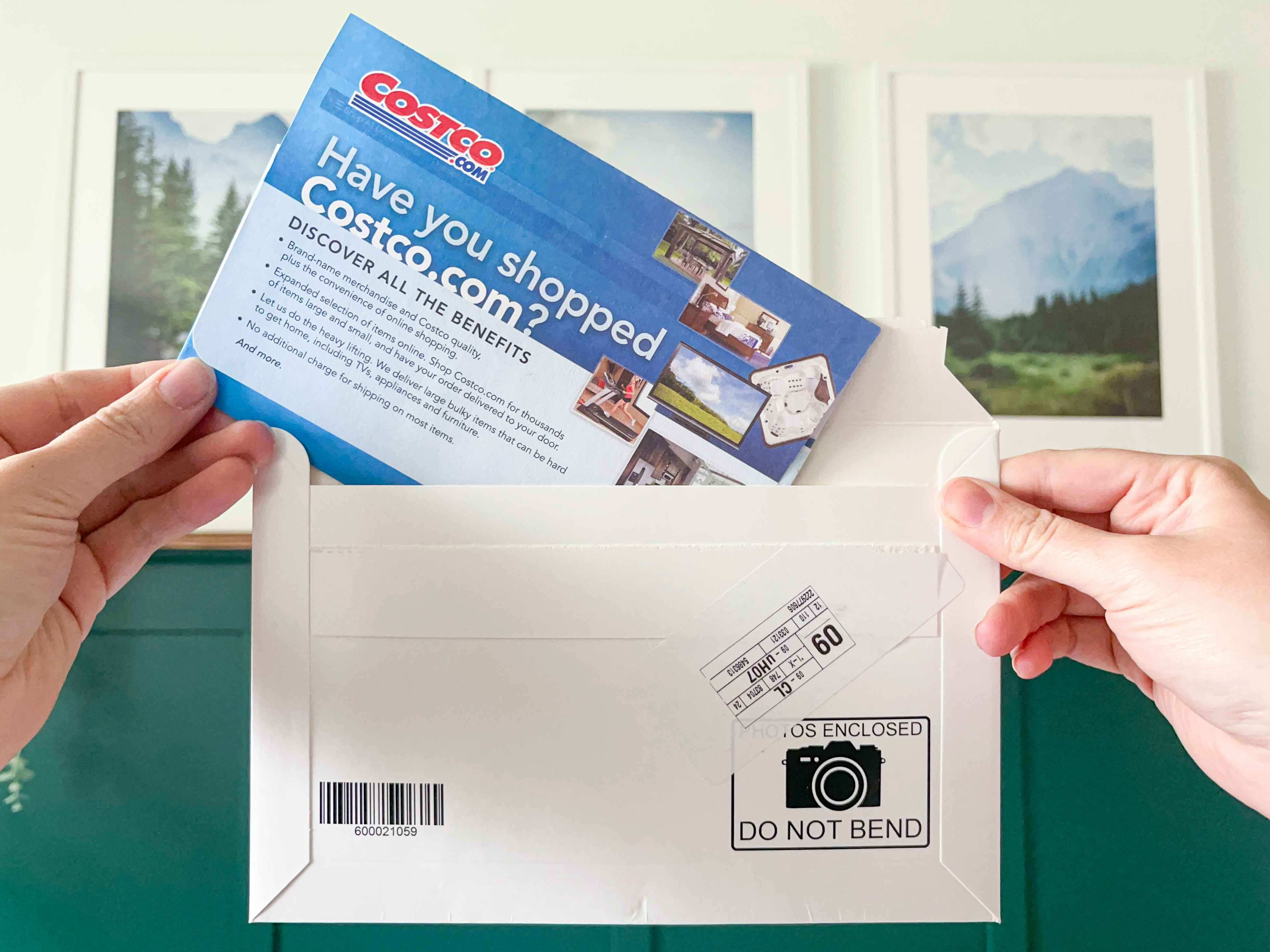 Photos and a costco.com photo center envelope held in a persons hands