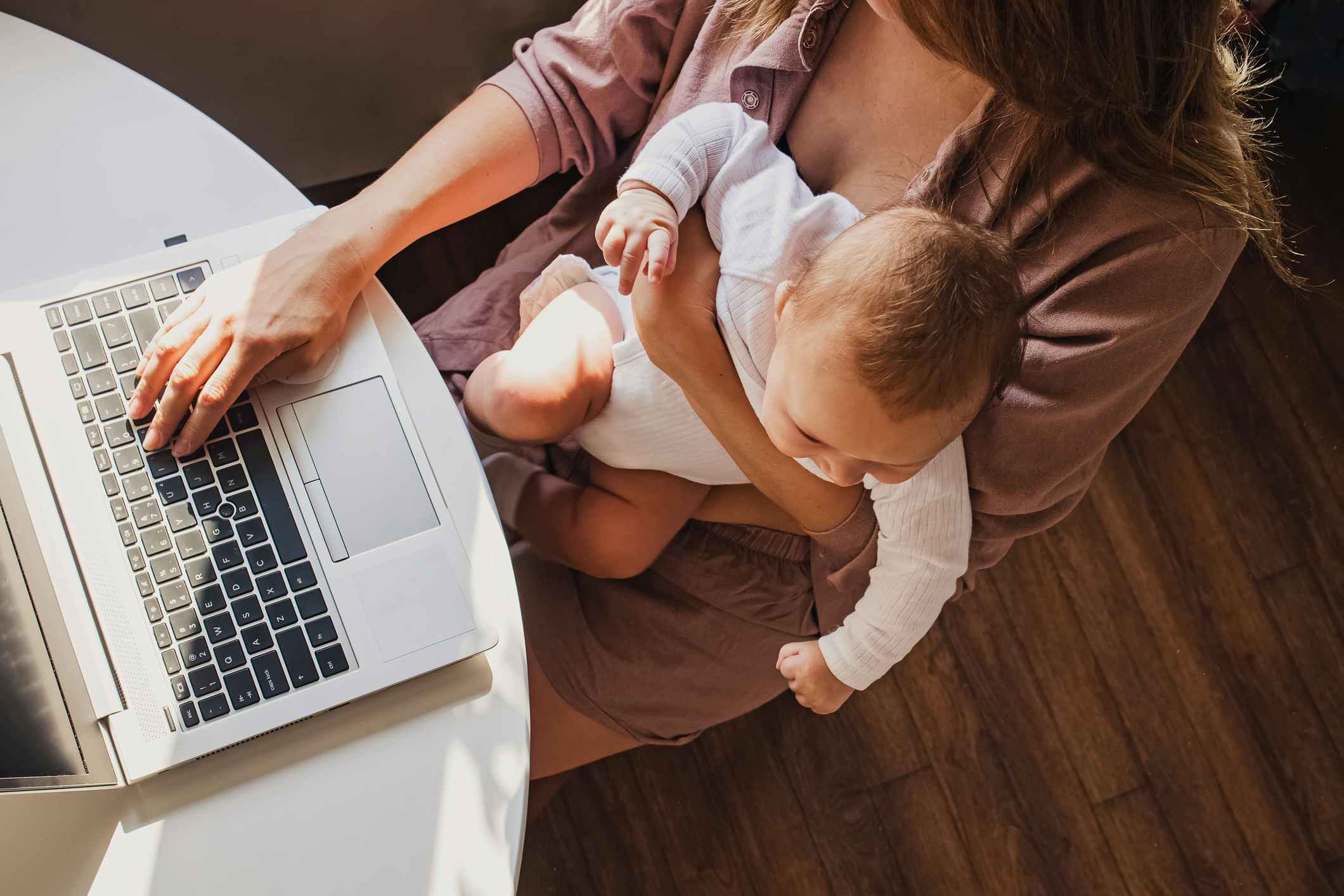 young mother working on laptop with baby on lap
