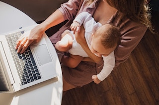 young mother working on laptop with baby on lap