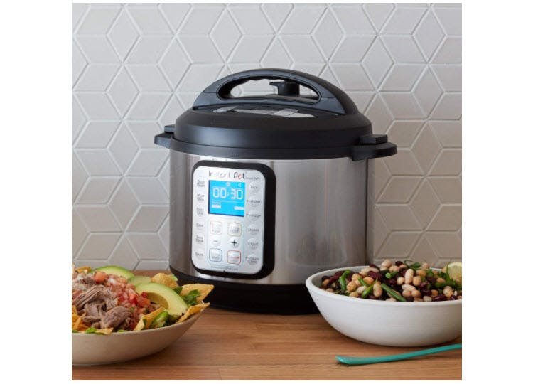 Instant Pot WiFi pressure cooker sitting on a counter with bowls of food surrounding it.