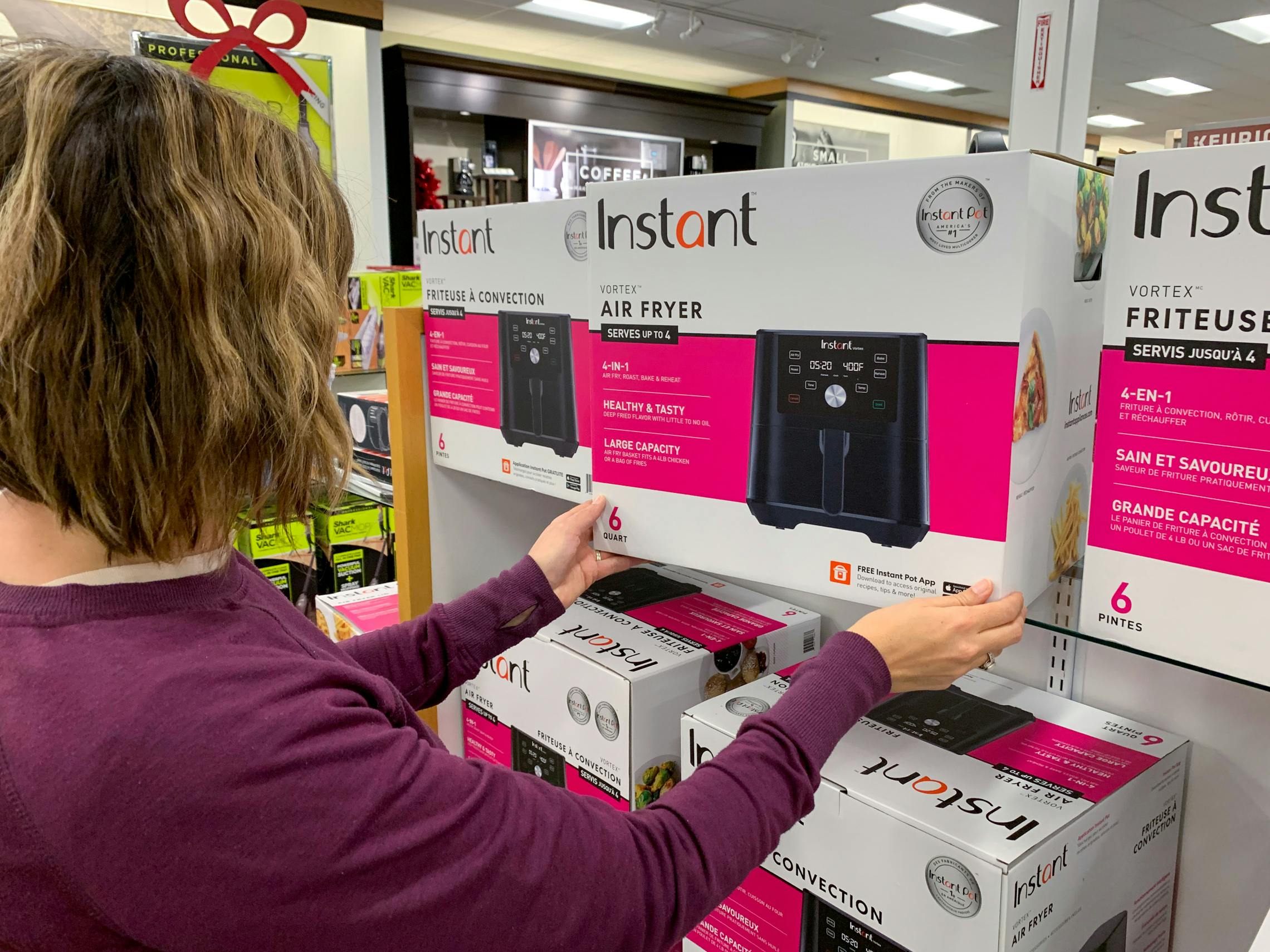 Woman pulling an Instant Air Fryer off the shelf in a store