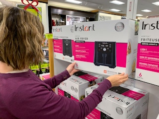 Woman pulling an Instant Air Fryer off the shelf in a store