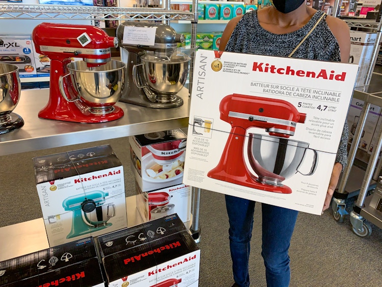 A person holding a KitchenAid mixer inside Kohls