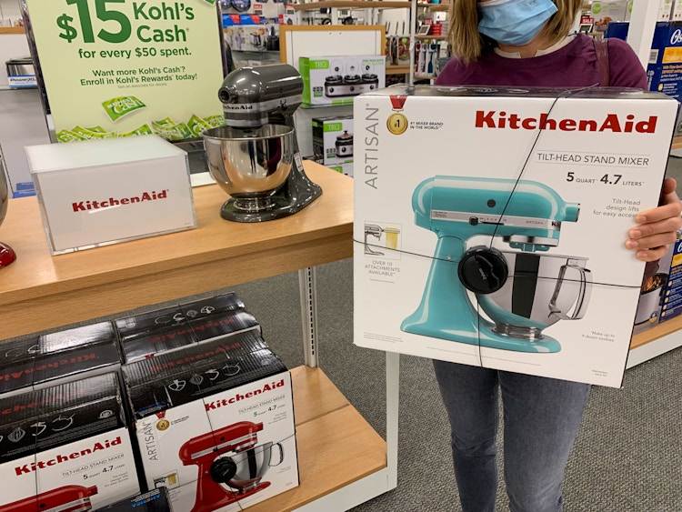 someone holding a kitchenaid stand mixer in front of a kohls cash holiday shopping sign at kohls