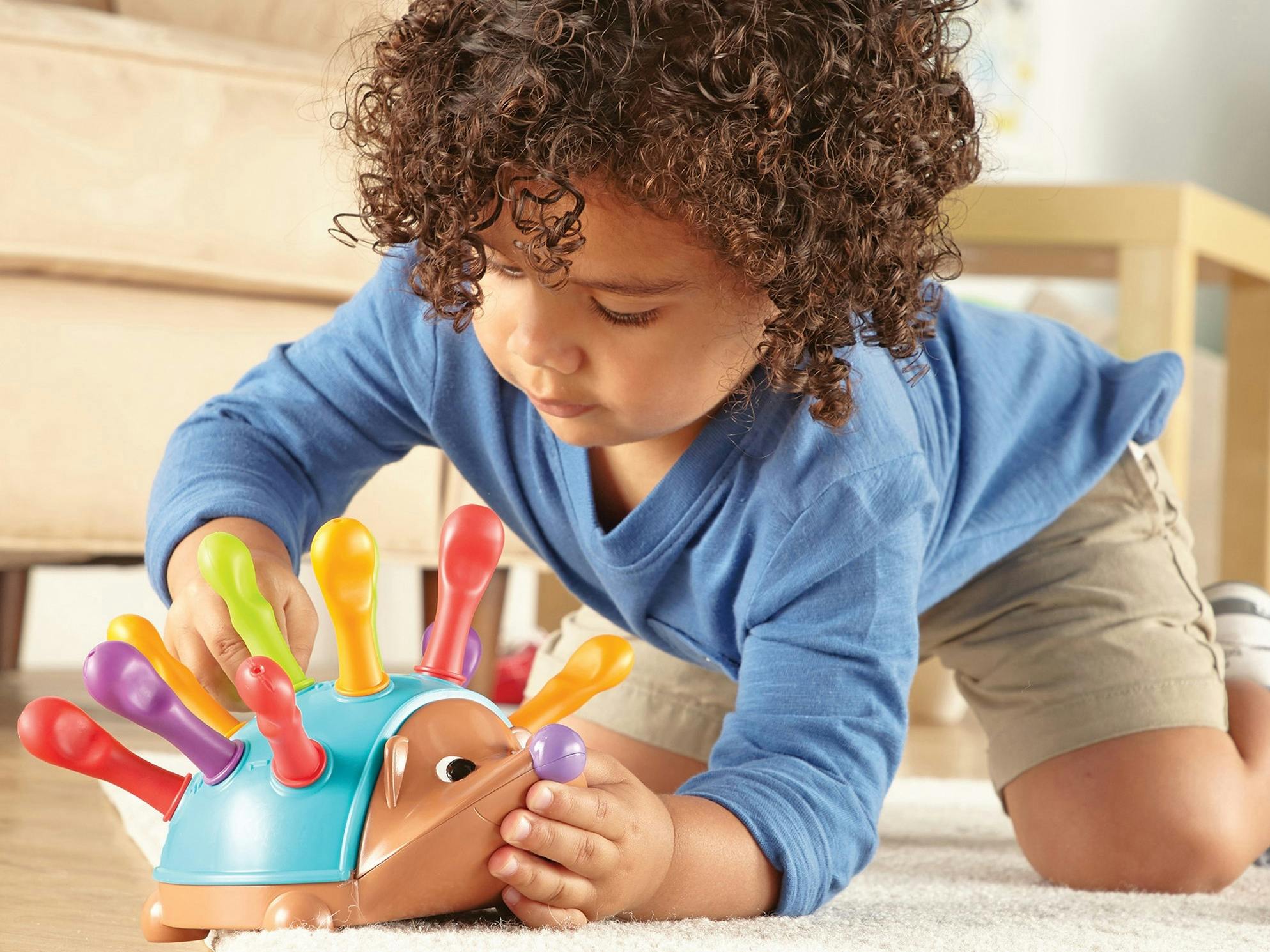 A child playing with a Spike The Fine Motor Hedgehog toy.