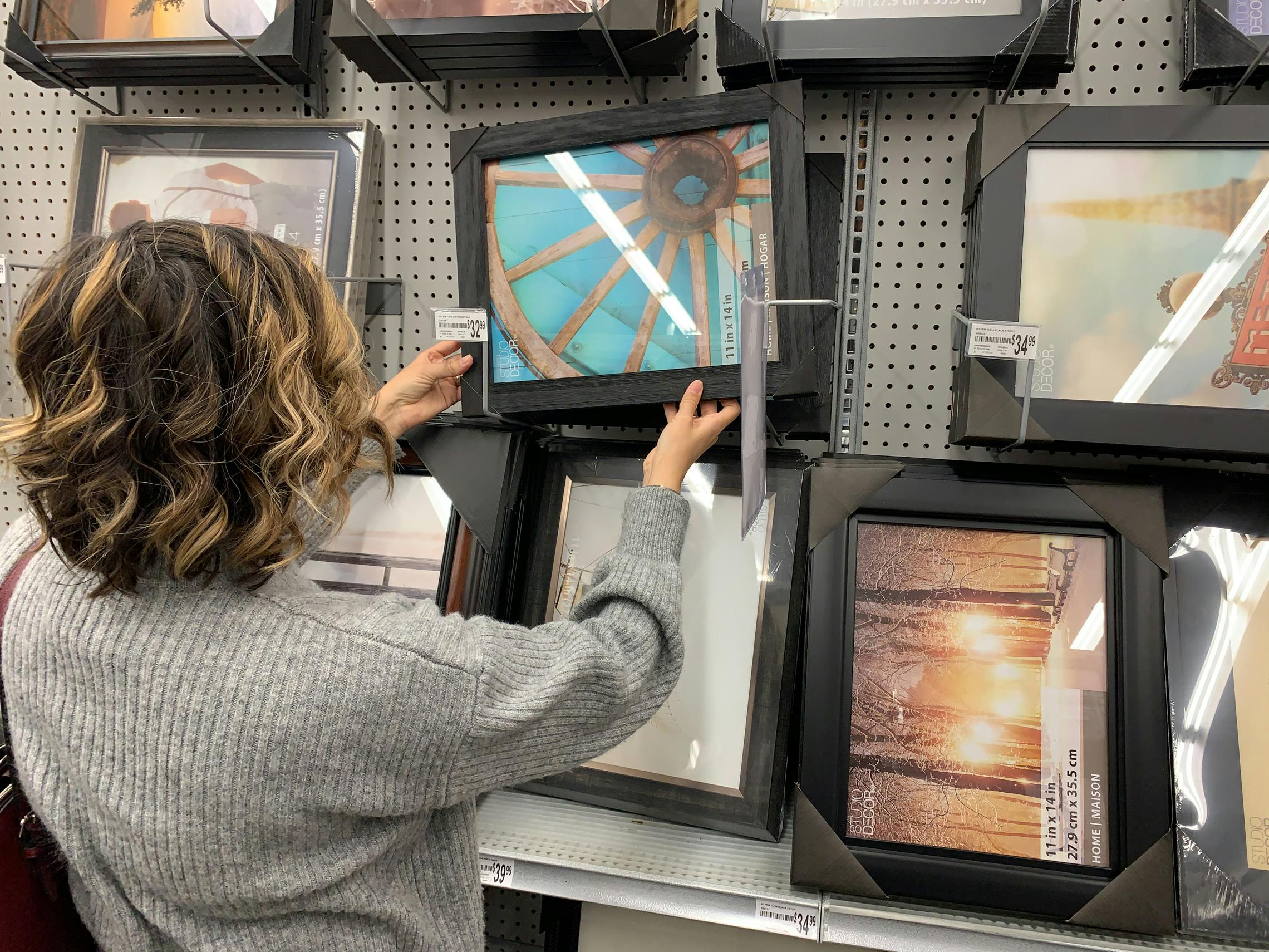 woman at Michaels picking up a frame in front an aisle of frames