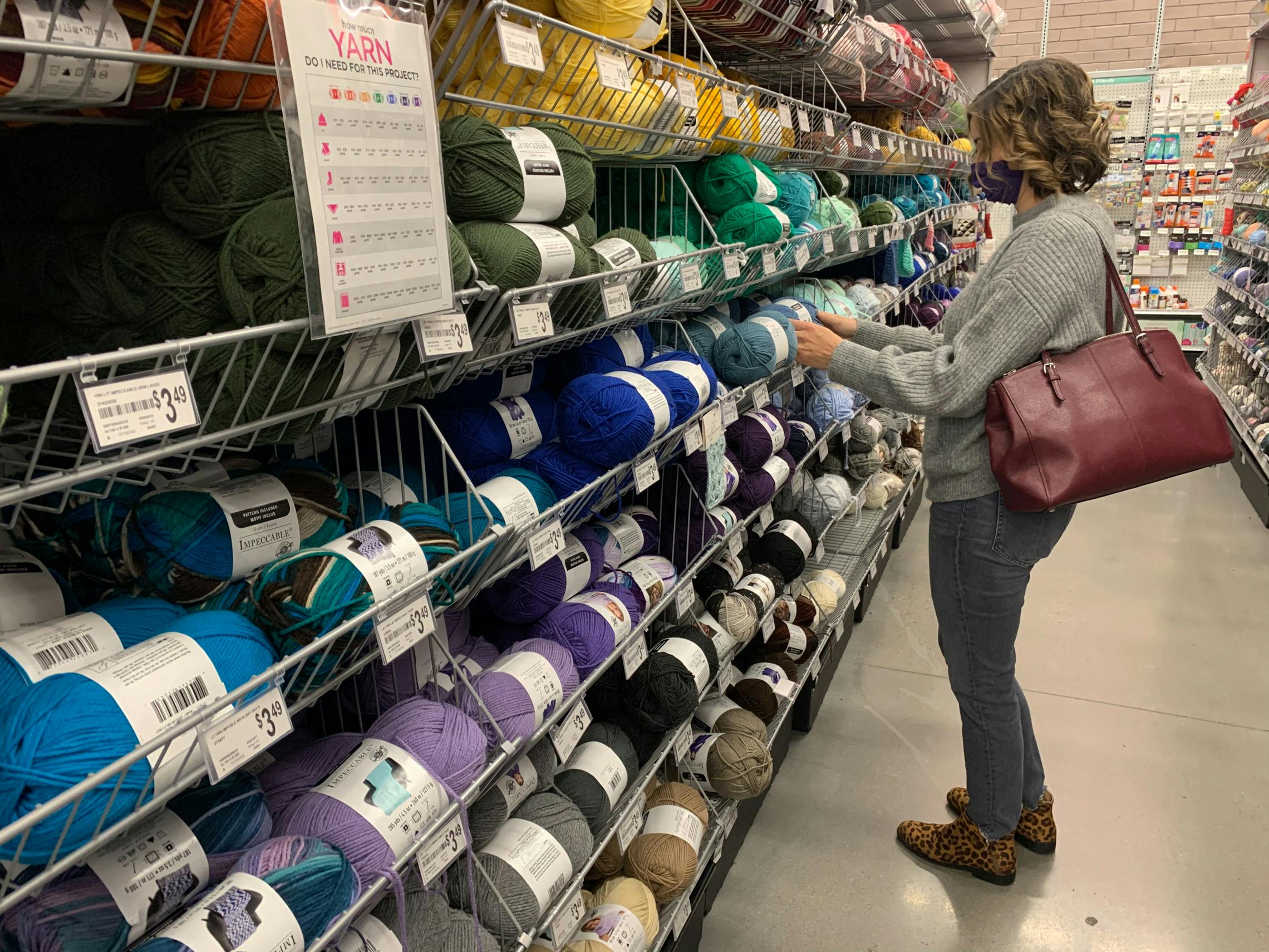 woman at michaels looking through an aisle of yarn