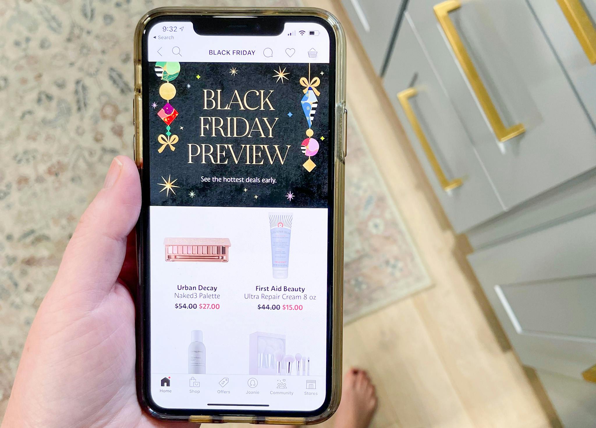 A person's hand holding an iPhone and looking at the Sephora Black Friday preview for 2021