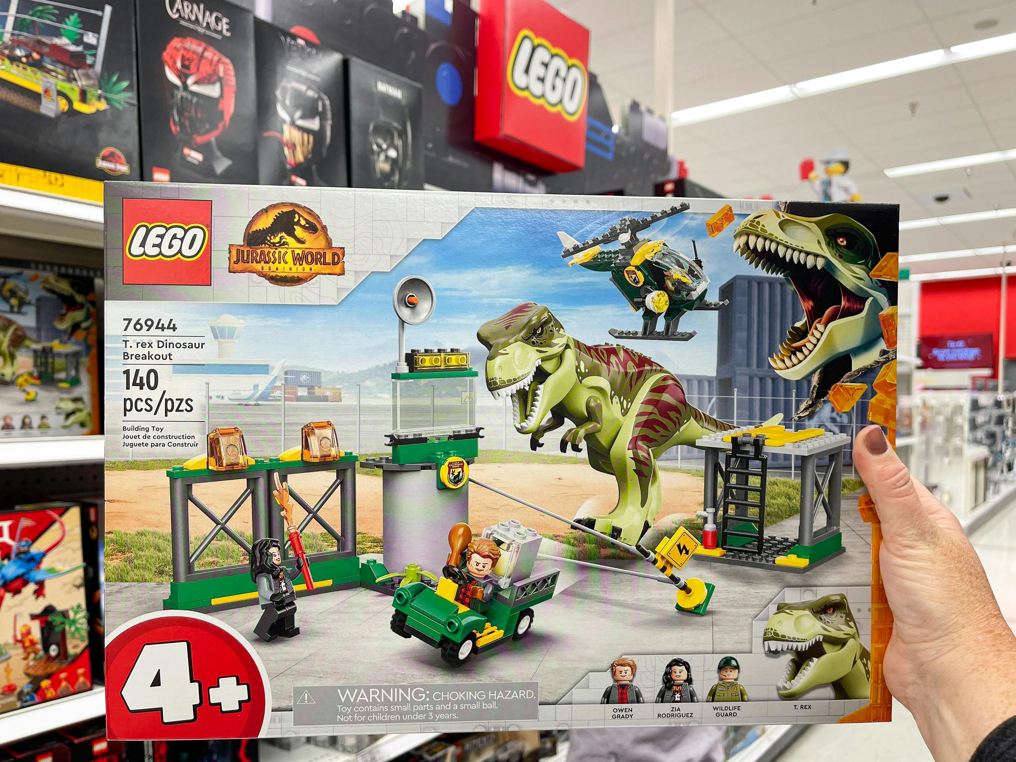 A person's hand holding a LEGO Jurassic World Dinosaur Breakout set inside Target