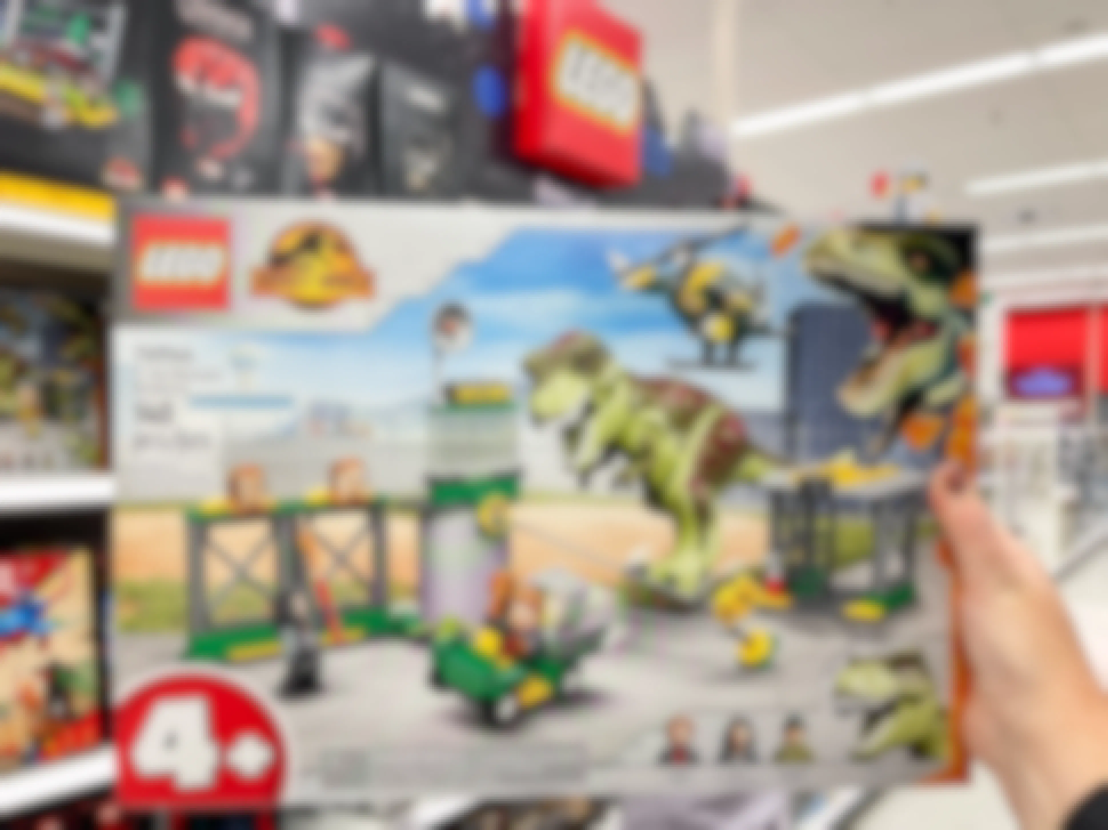 A person's hand holding a LEGO Jurassic World Dinosaur Breakout set inside Target