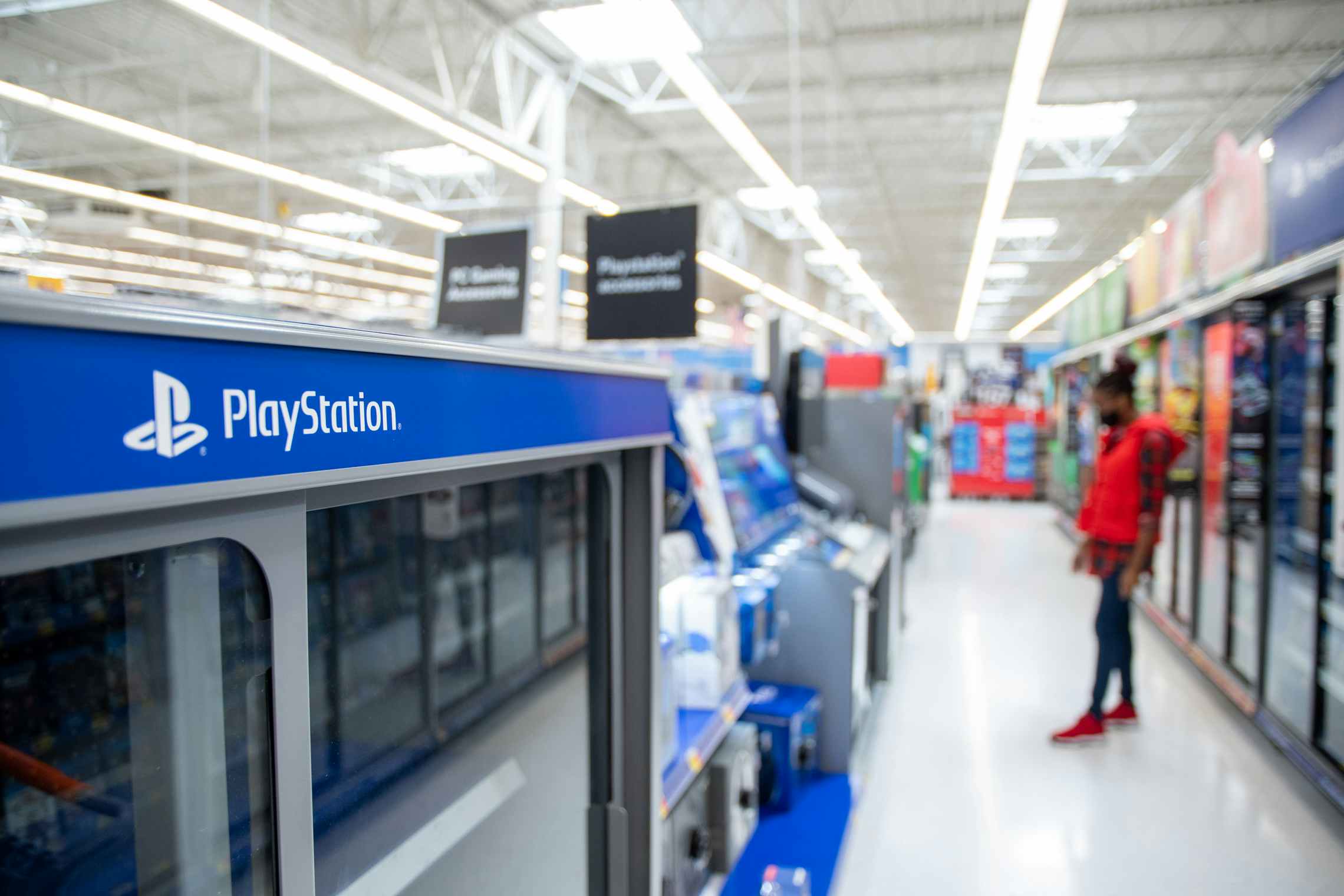 A person shopping in the PlayStation aisle at Walmart.