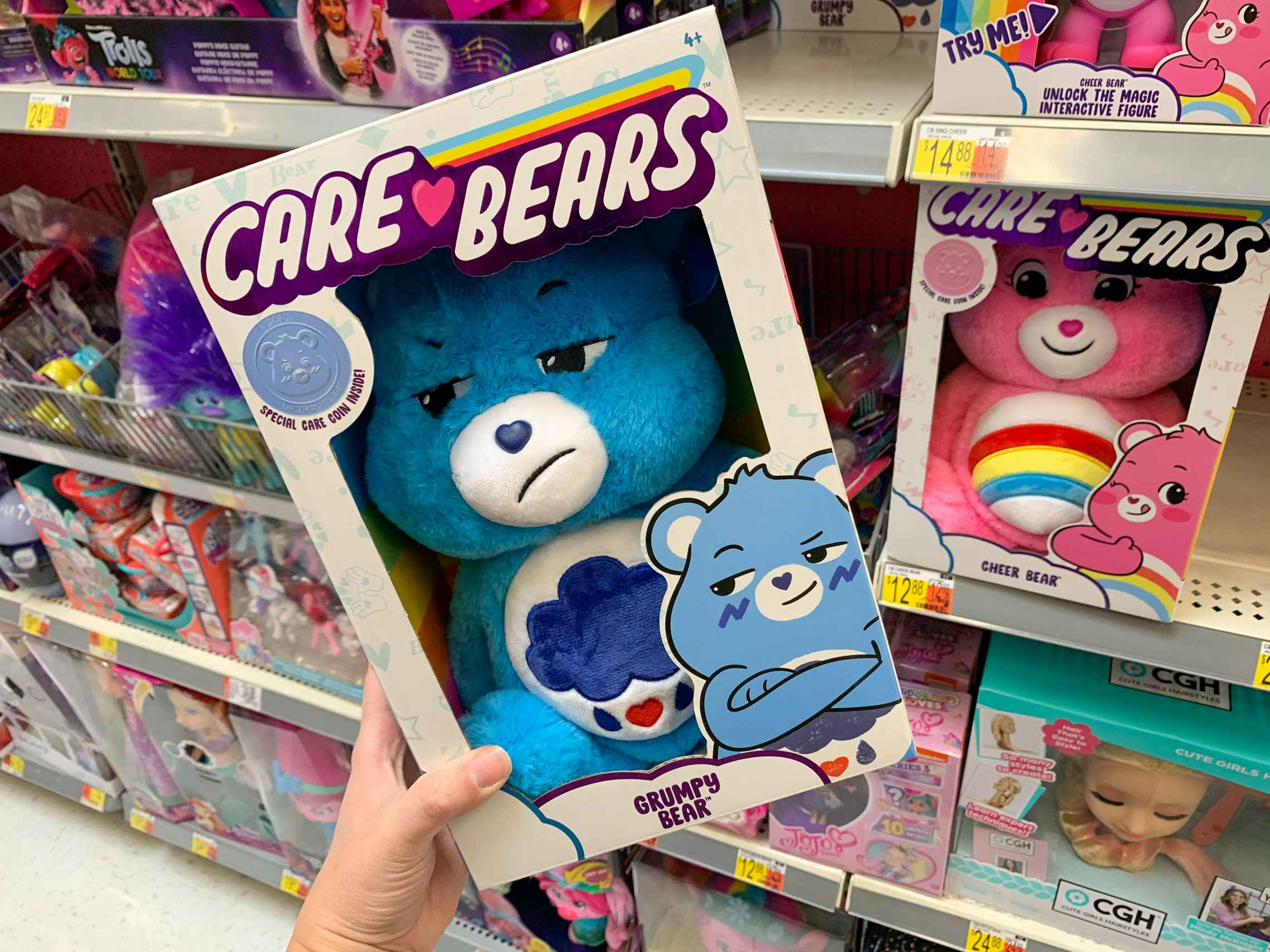 care bear grumpy bear plush held at an angle in front of other care bears on walmart shelf