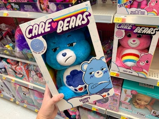 care bear grumpy bear plush held at an angle in front of other care bears on walmart shelf