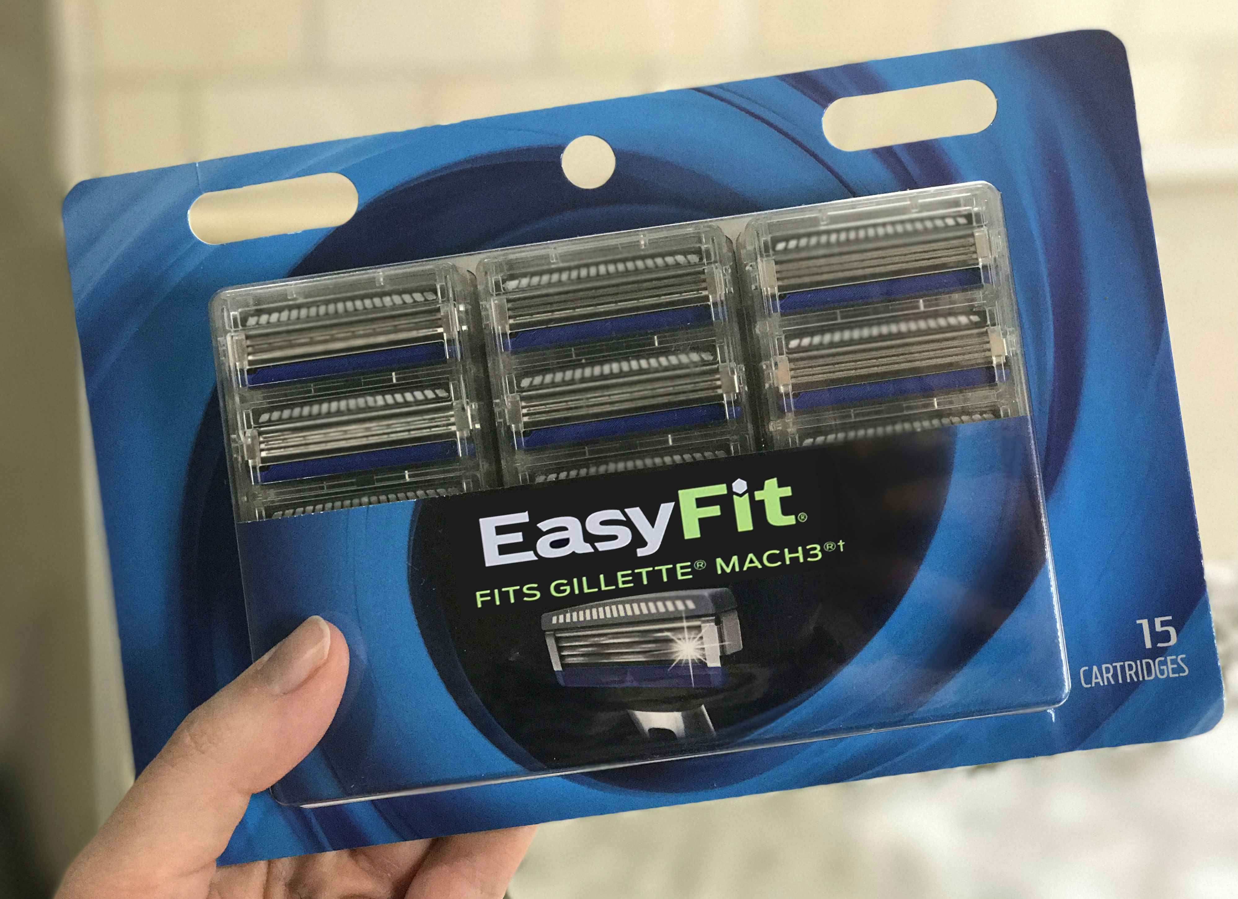 A person holding a pack of Amazon Easy Fit generic razor refills