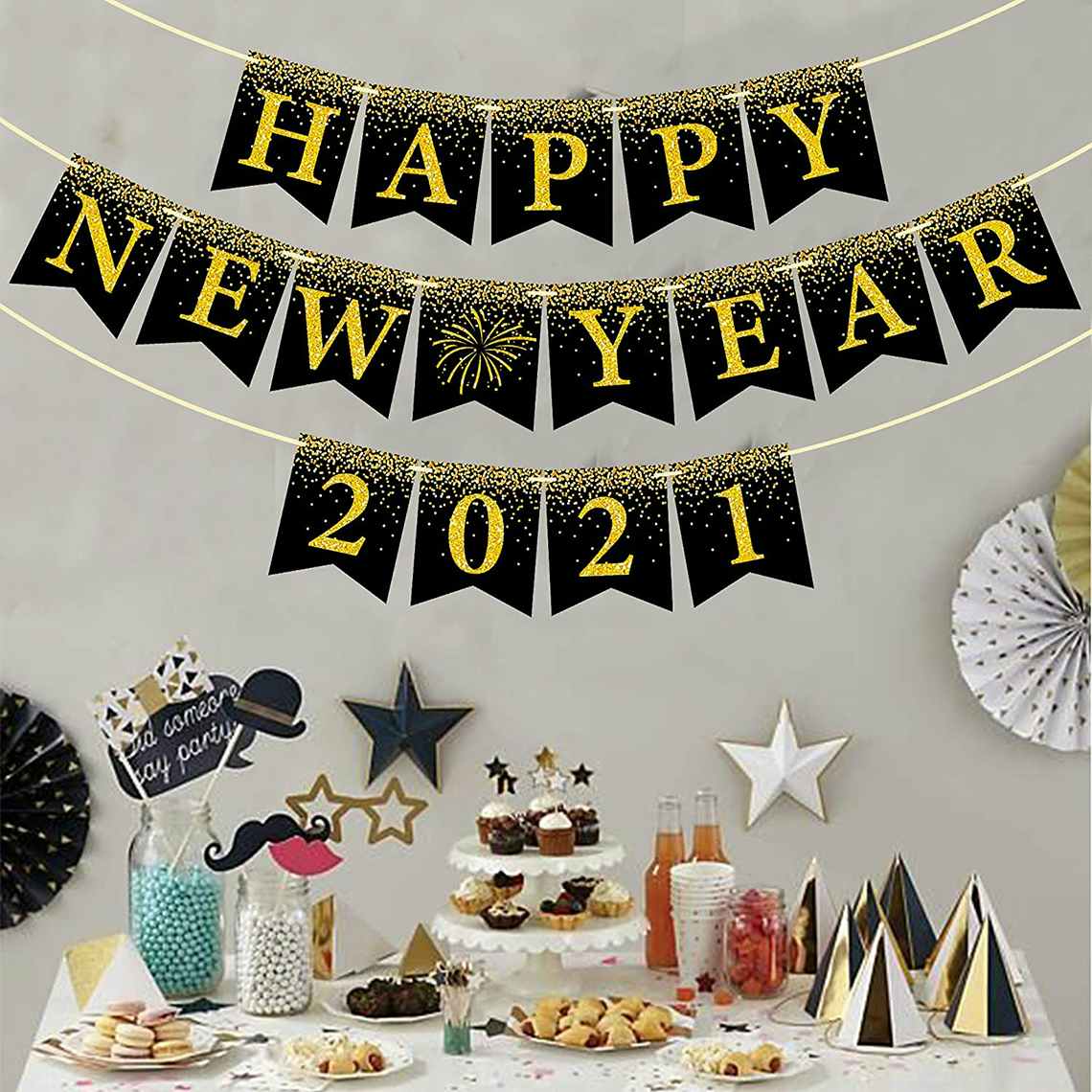 a wall with a happy new year 2021 sign and a table full of decor and food