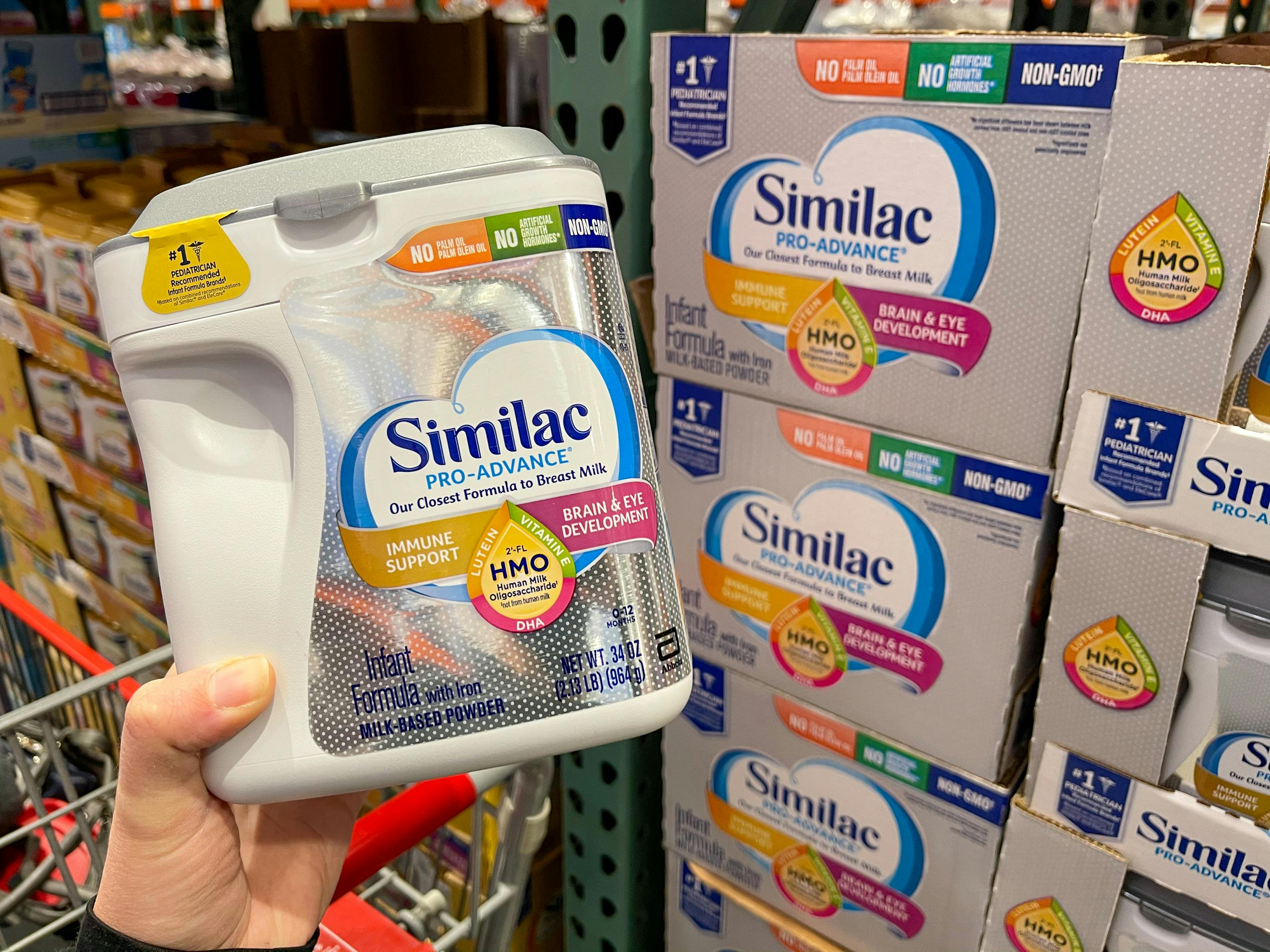 Similac baby formula held in front of a shelf at Costco.