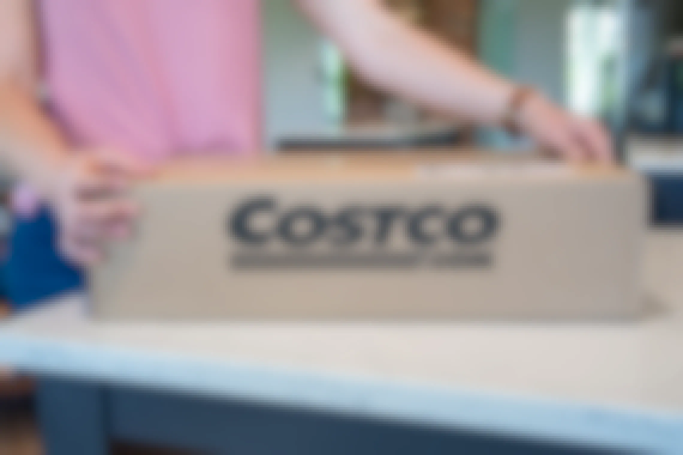 A person opening a Costco.com online order box.