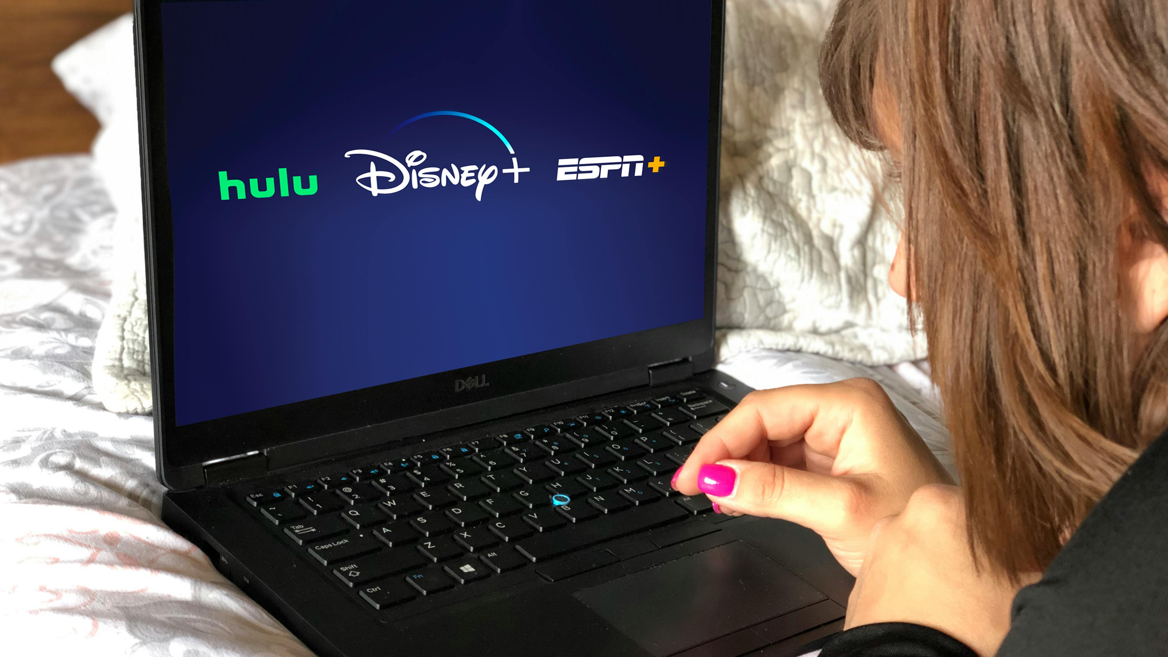 someone looking at laptop with Disney plus hulu and espn