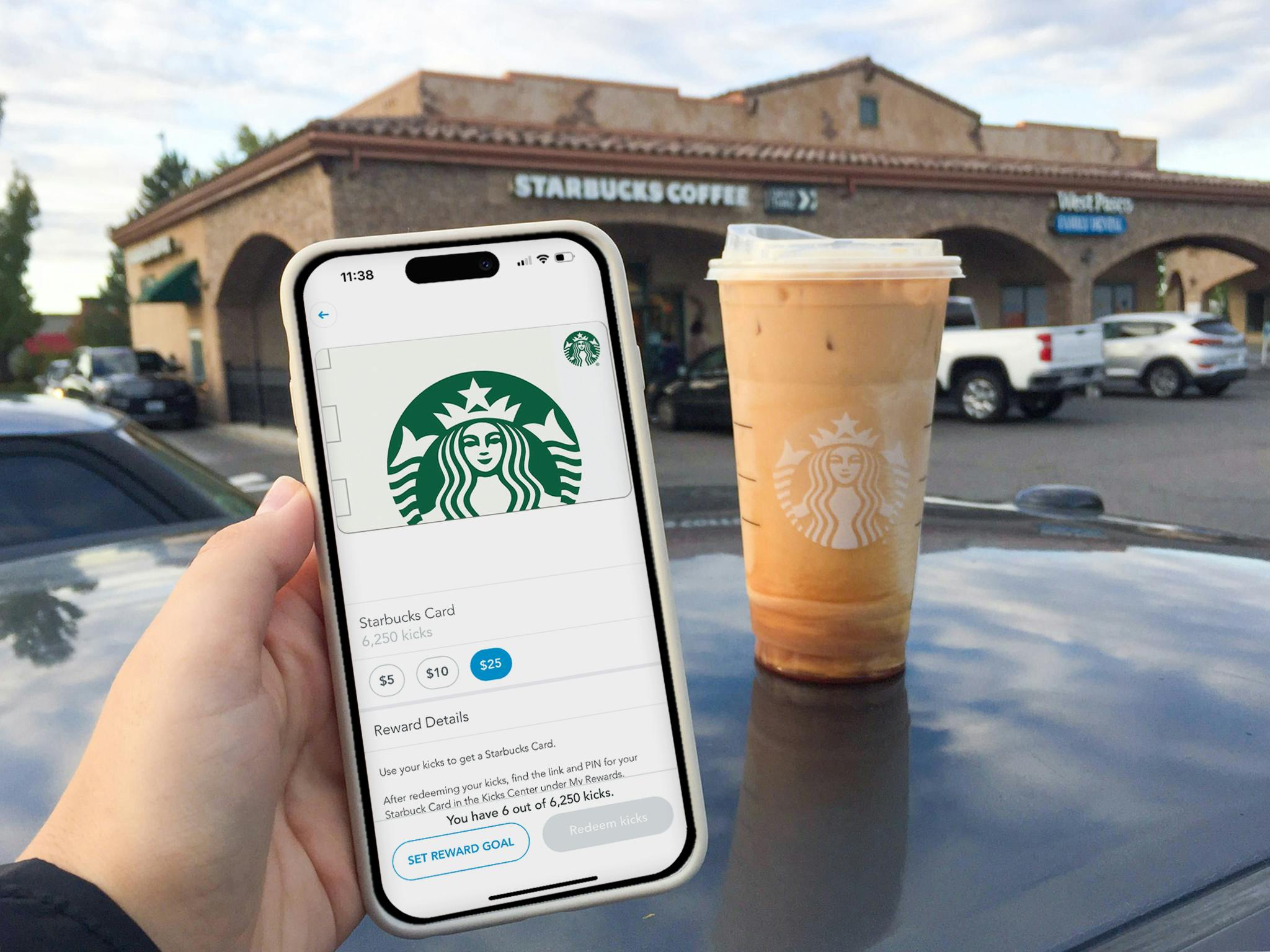 Someone holding a phone displaying a Shopkick Strabucks gift card reward in front of a Starbucks coffee and store