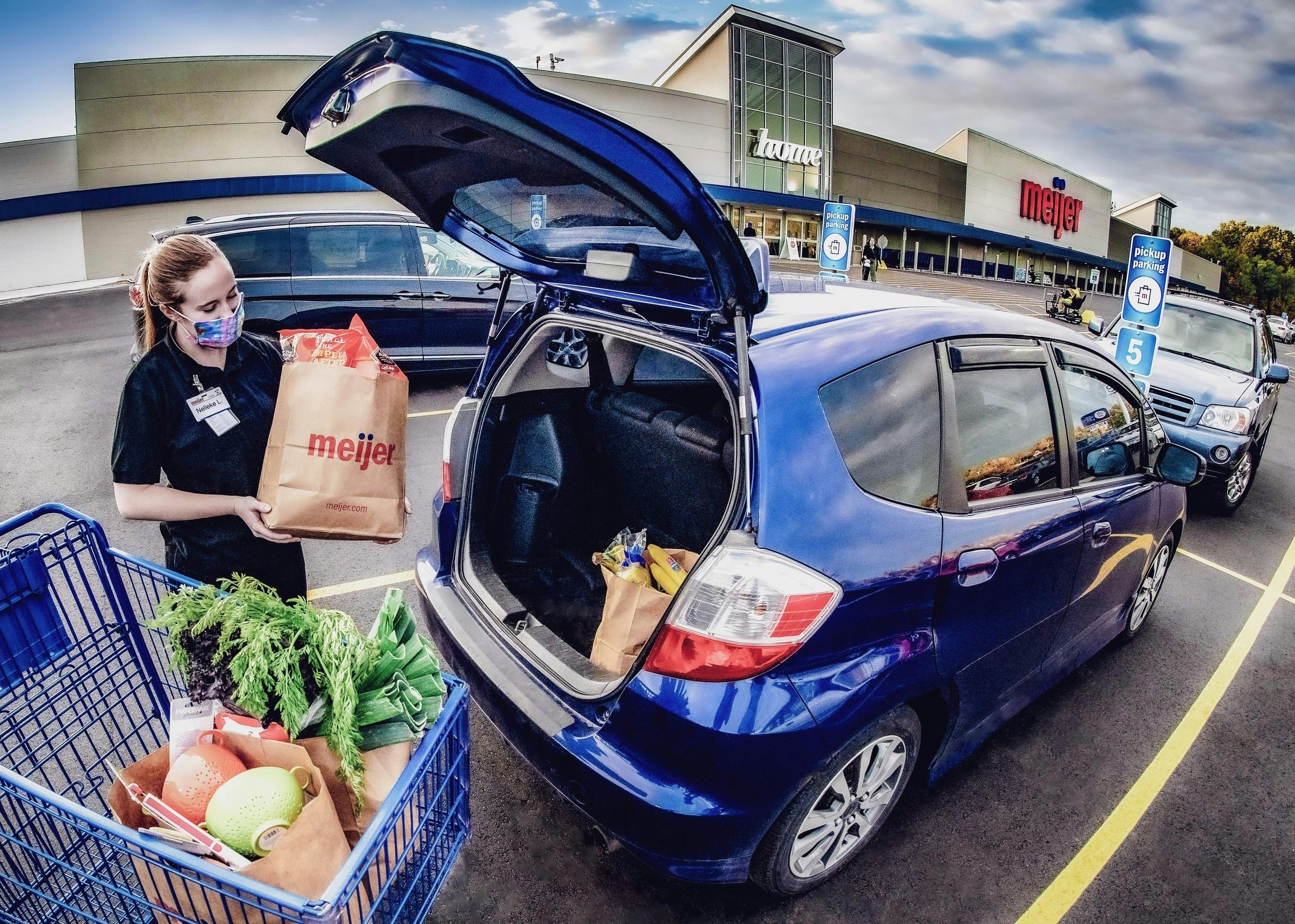Meijer employee loading a trunk with groceries at a Meijer store.