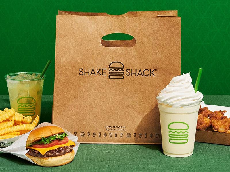 A Shake Shack bag and food on a green background
