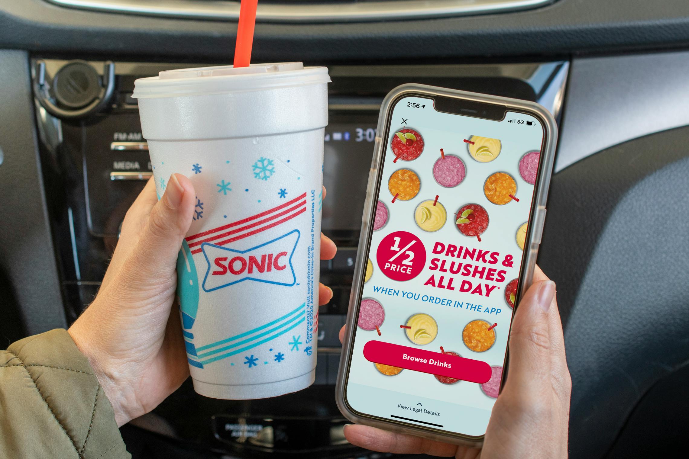 1/2 drinks and slushes all day" ad inside the Sonic app on a cell phone, next to a sonic cup.