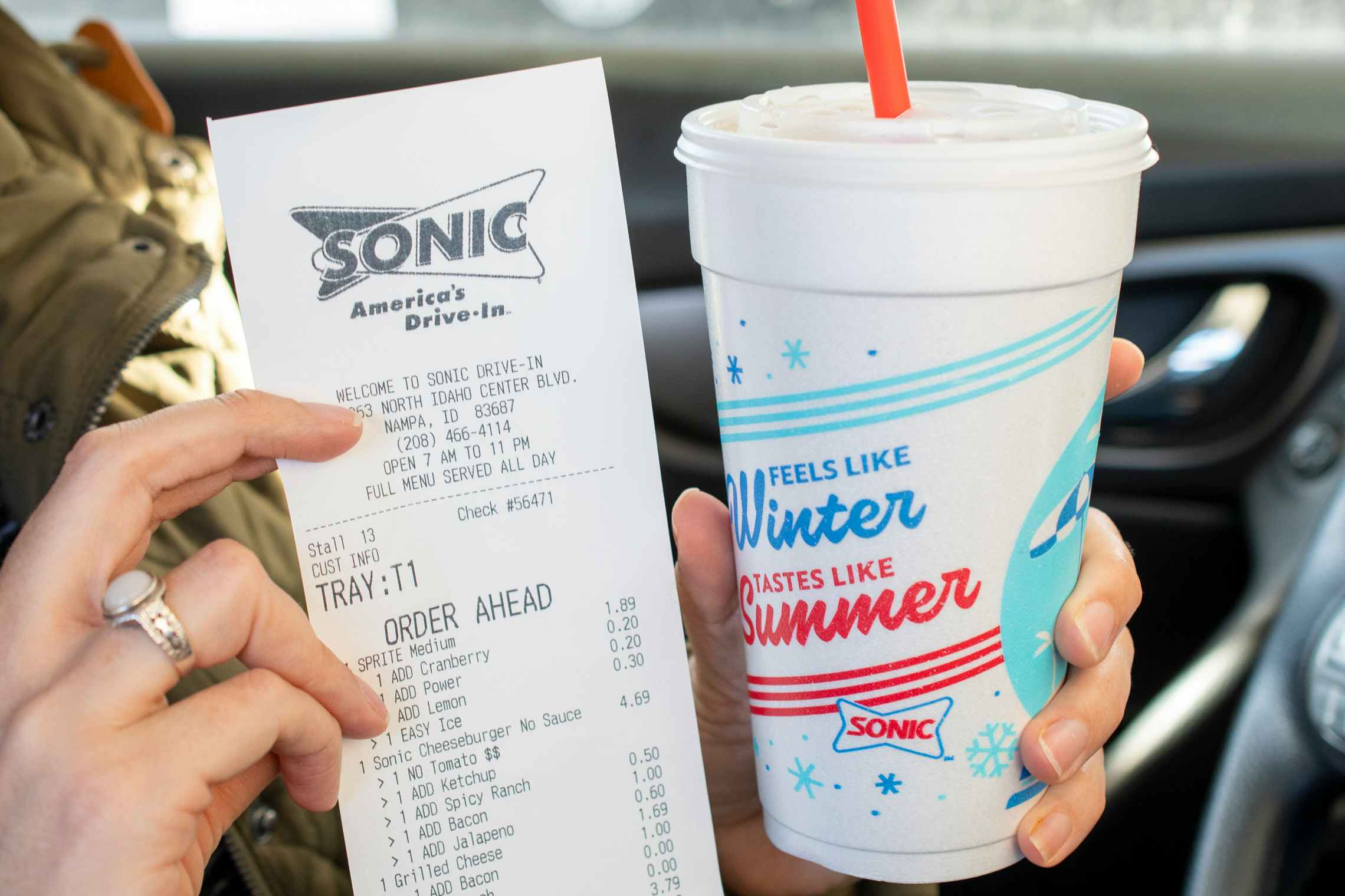 A person holding a receipt next to a sonic beverage