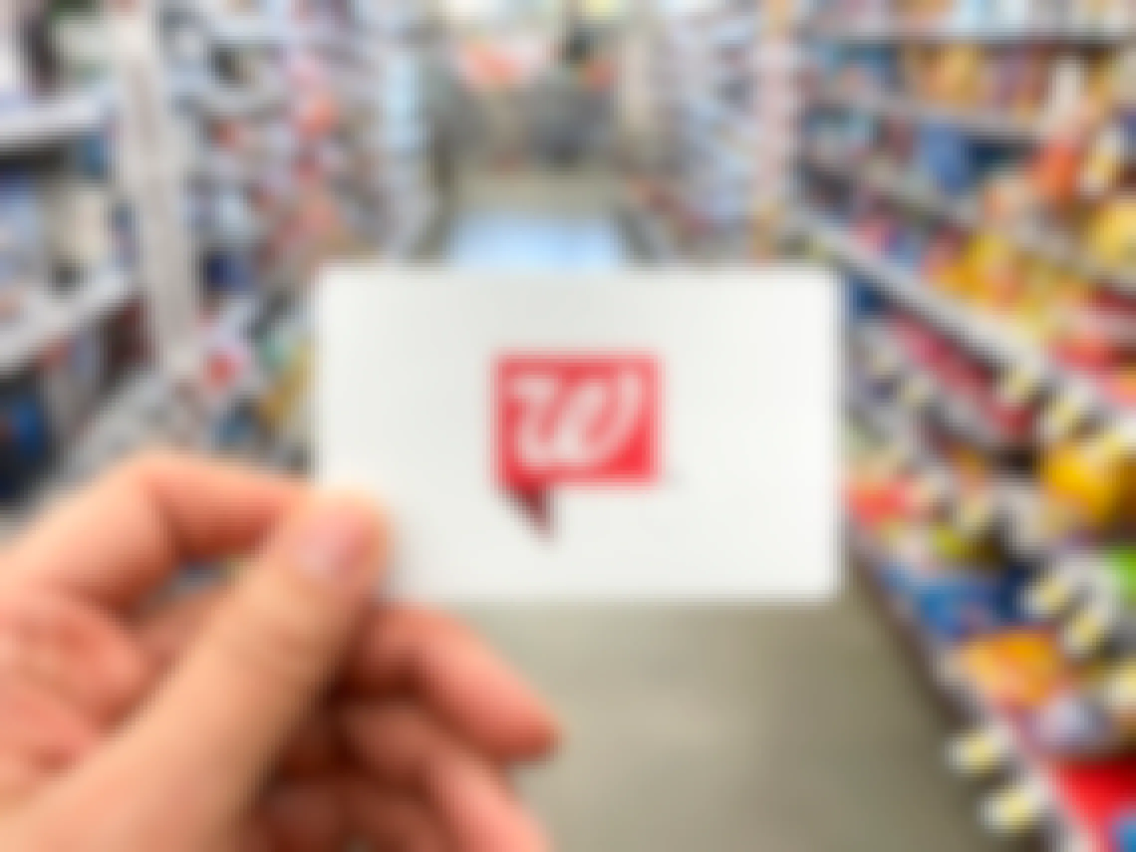 A person holding a Walgreens gift card inside Walgreens.