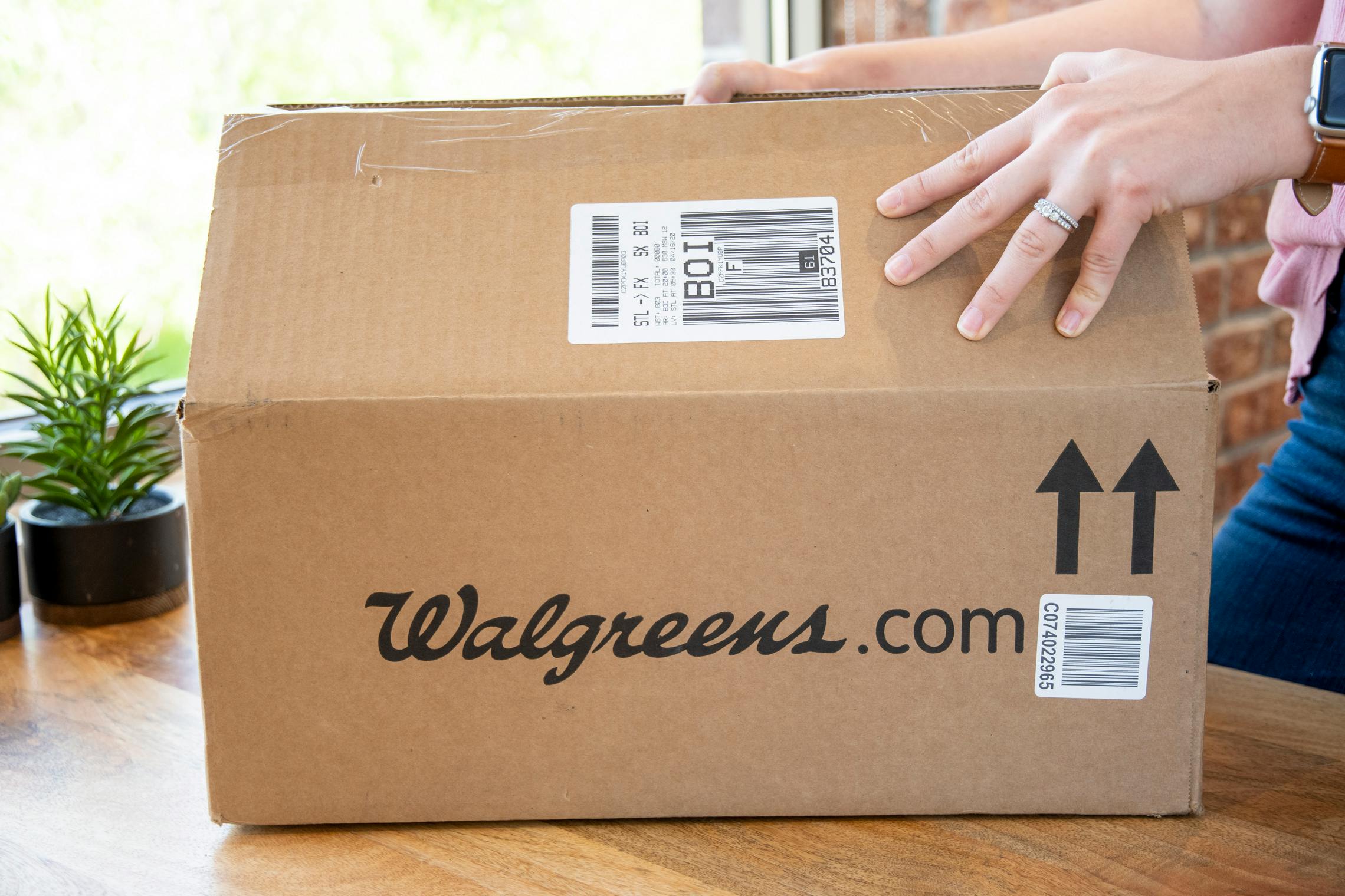 A person opening a Walgreens.com delivery box.