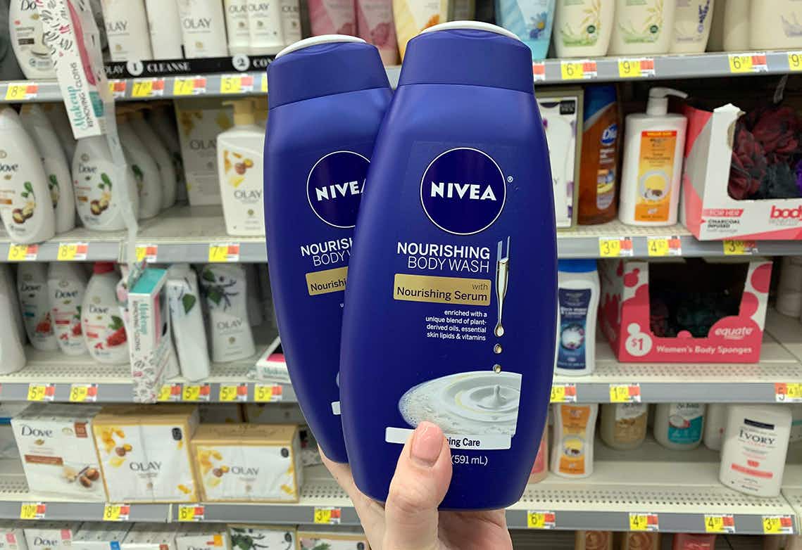A hand holding Nivea body wash in a store aisle.