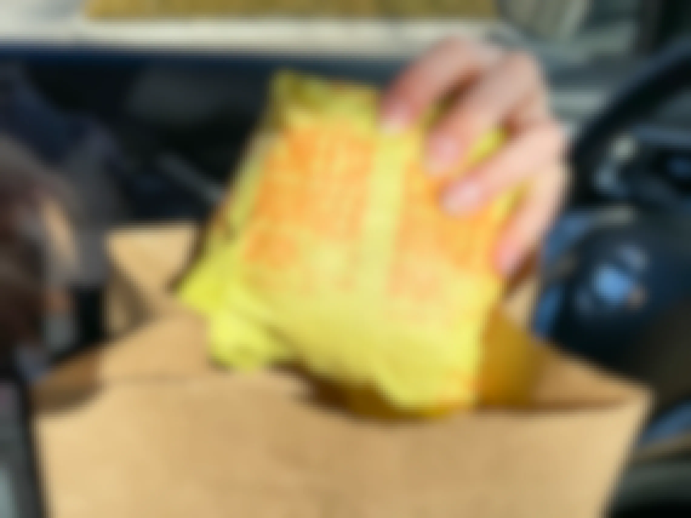 A person pulling a wrapped McDonald's cheeseburger out of a McDonald's bag while sitting in their car.
