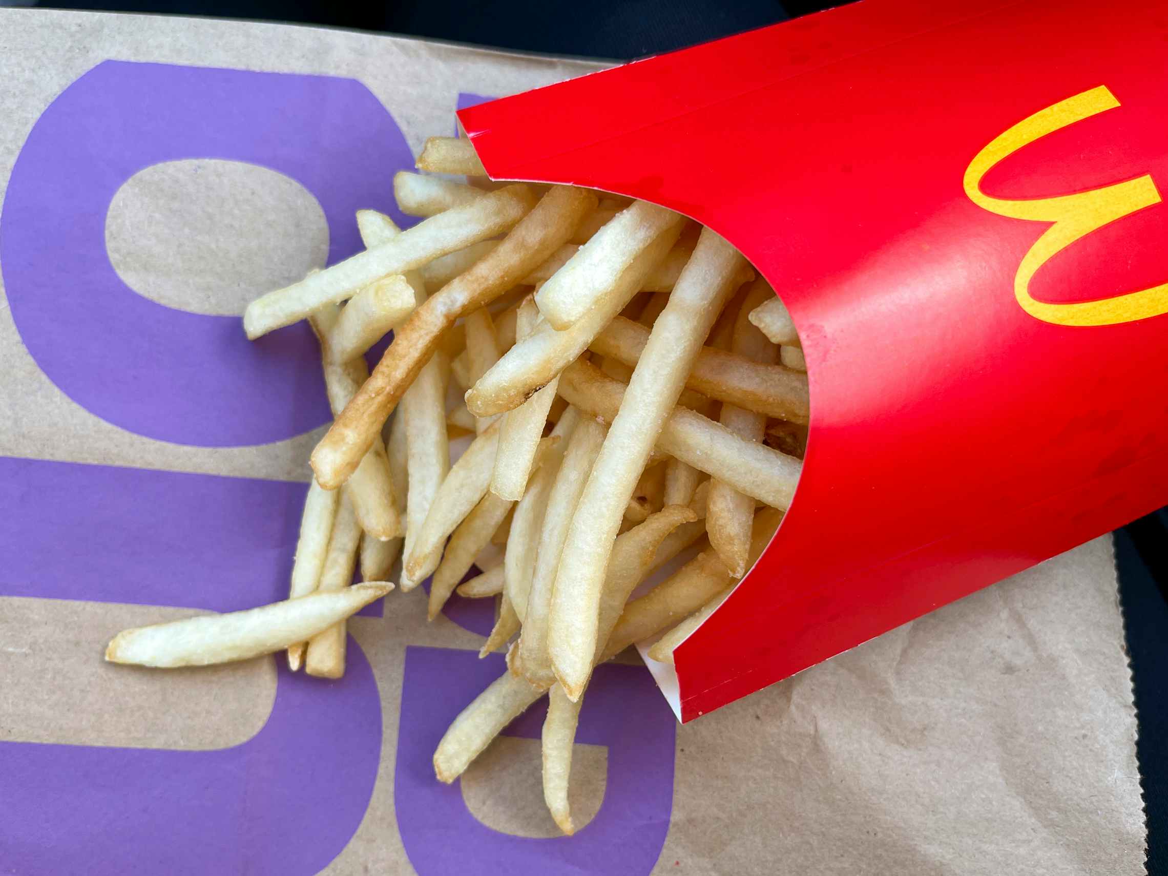 A close-up of a box of McDonald's fries lying on a McDonald's bag.