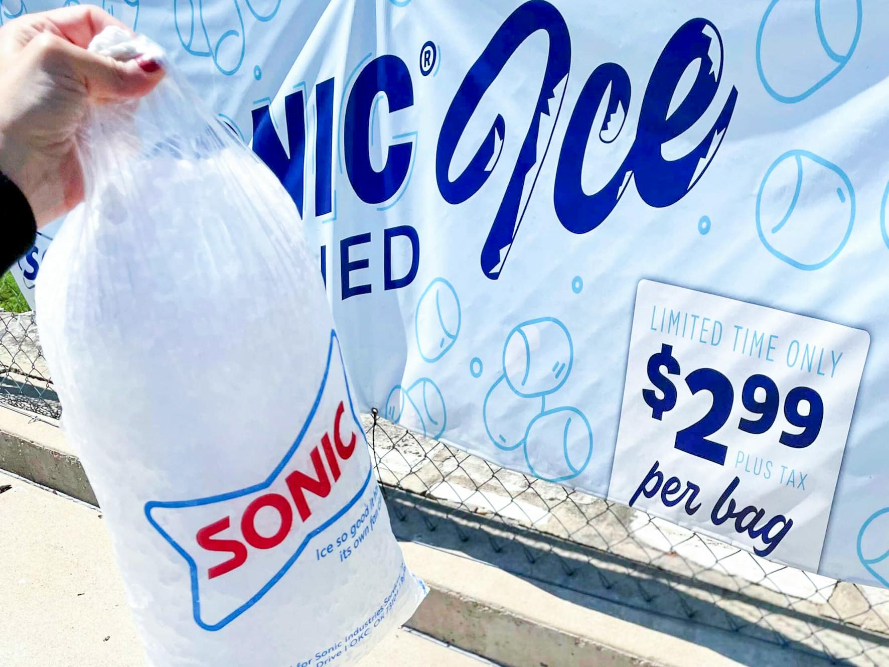 A person holding a bag of Sonic ice in front of a sign that says $2.99 per bag.