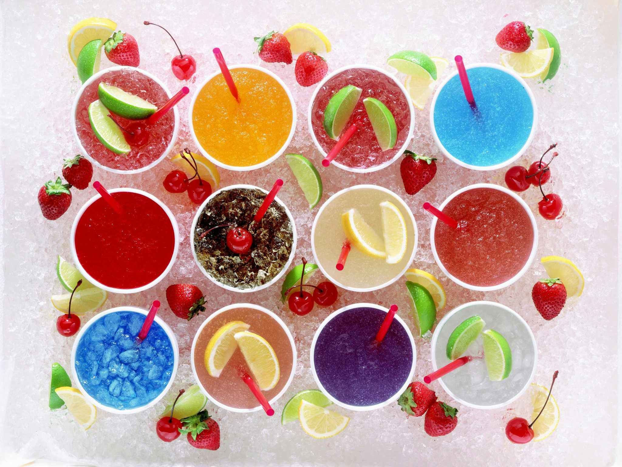 12 drink cups full of colorful beverages sitting on ice.