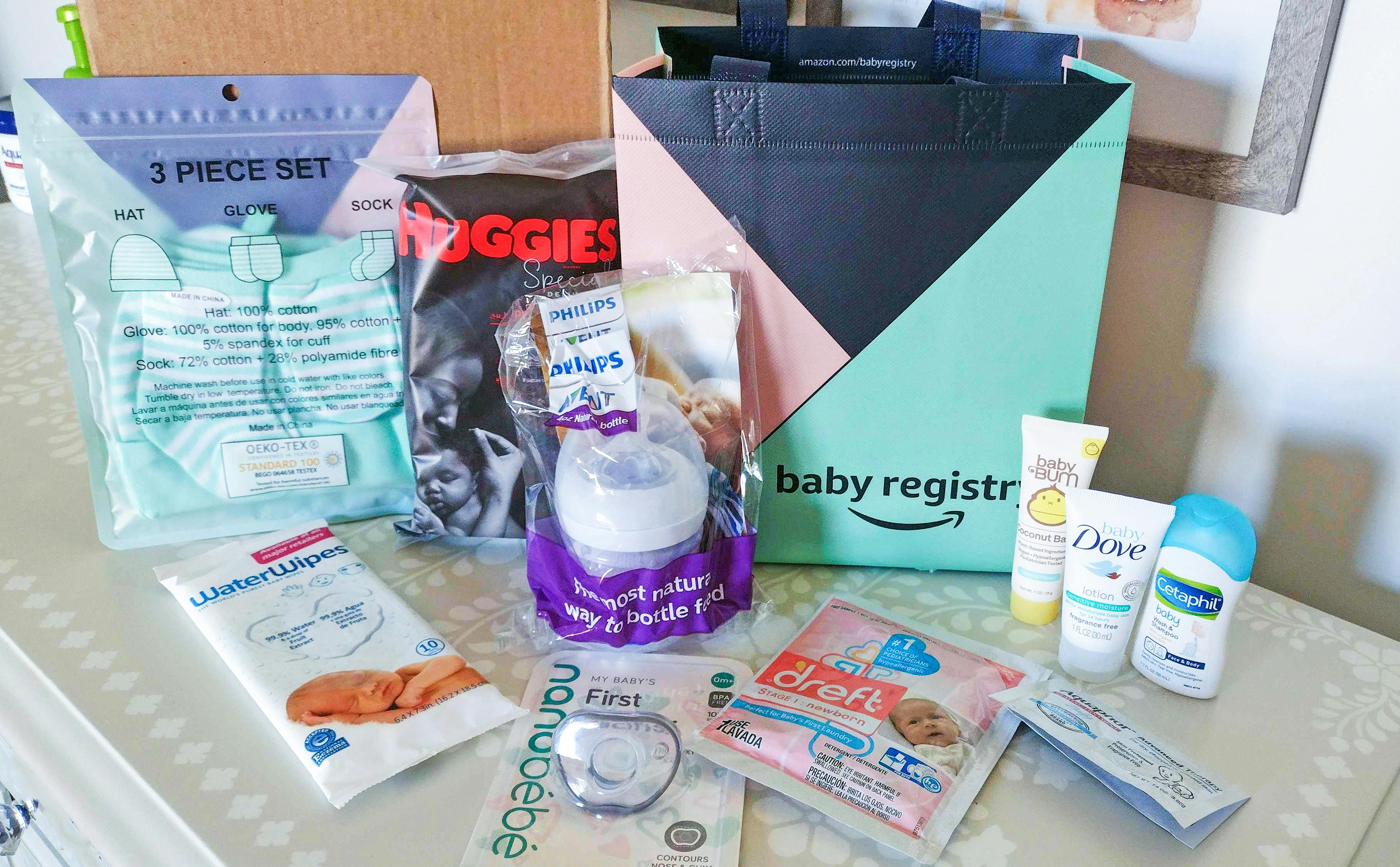 An Amazon Baby Registry reusable shopping bag sitting on a table surrounded with various baby products.