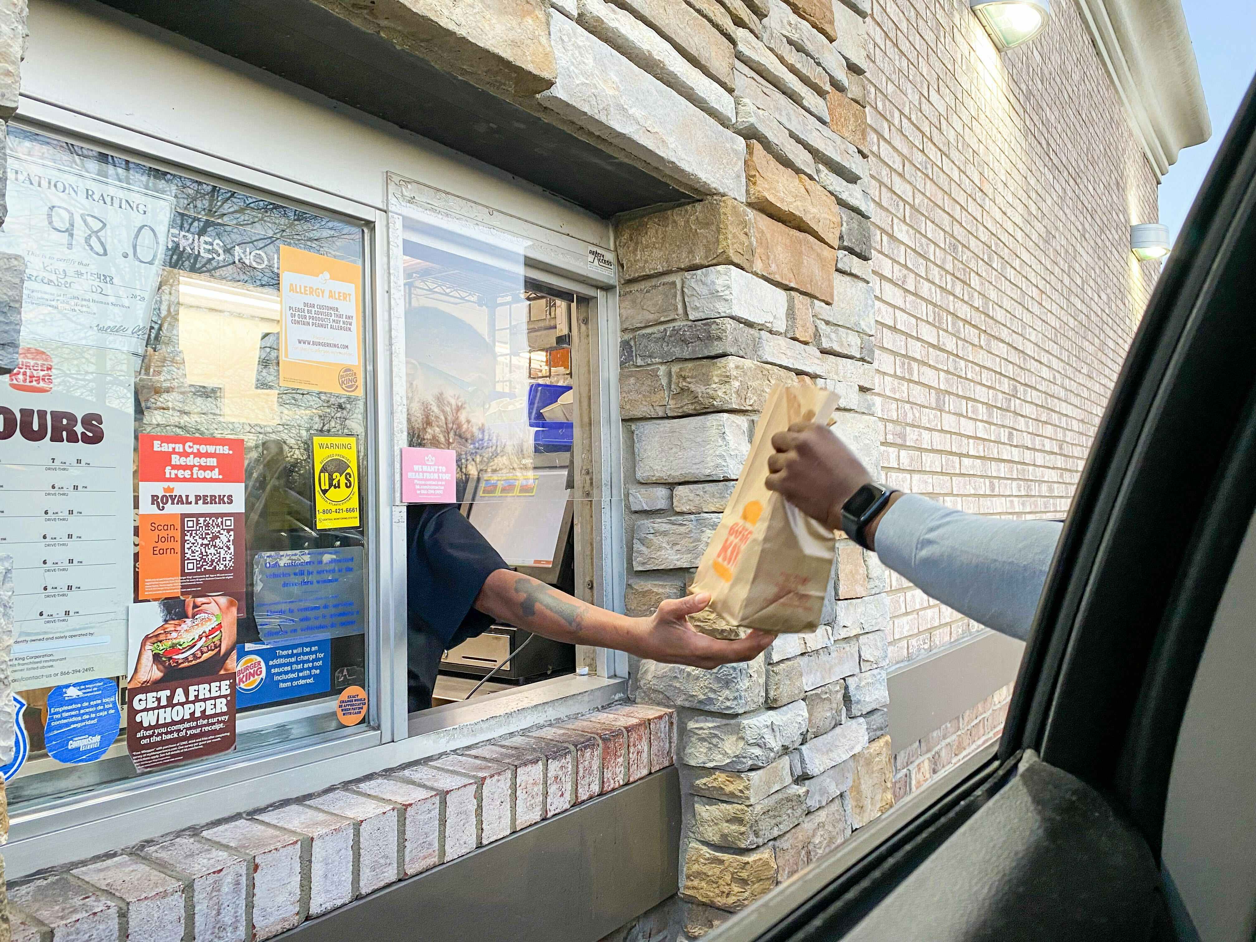 a person grabing burget king out of the drive thru window 