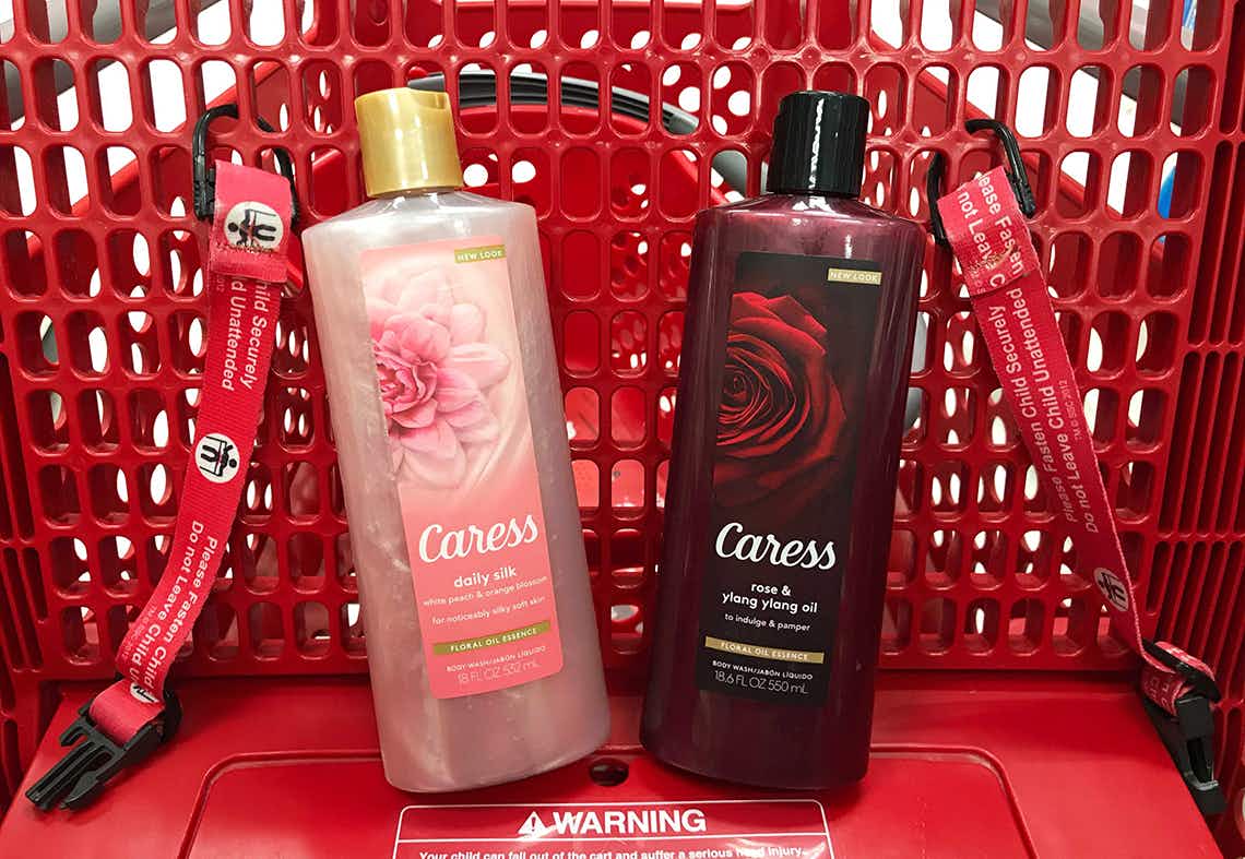Two bottles of Caress body wash sitting in the basket of a Target shopping cart.