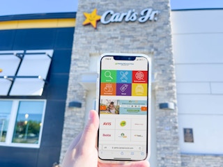 Cell phone showing fast food deals at Restaurant.com with Carls Jr in the background