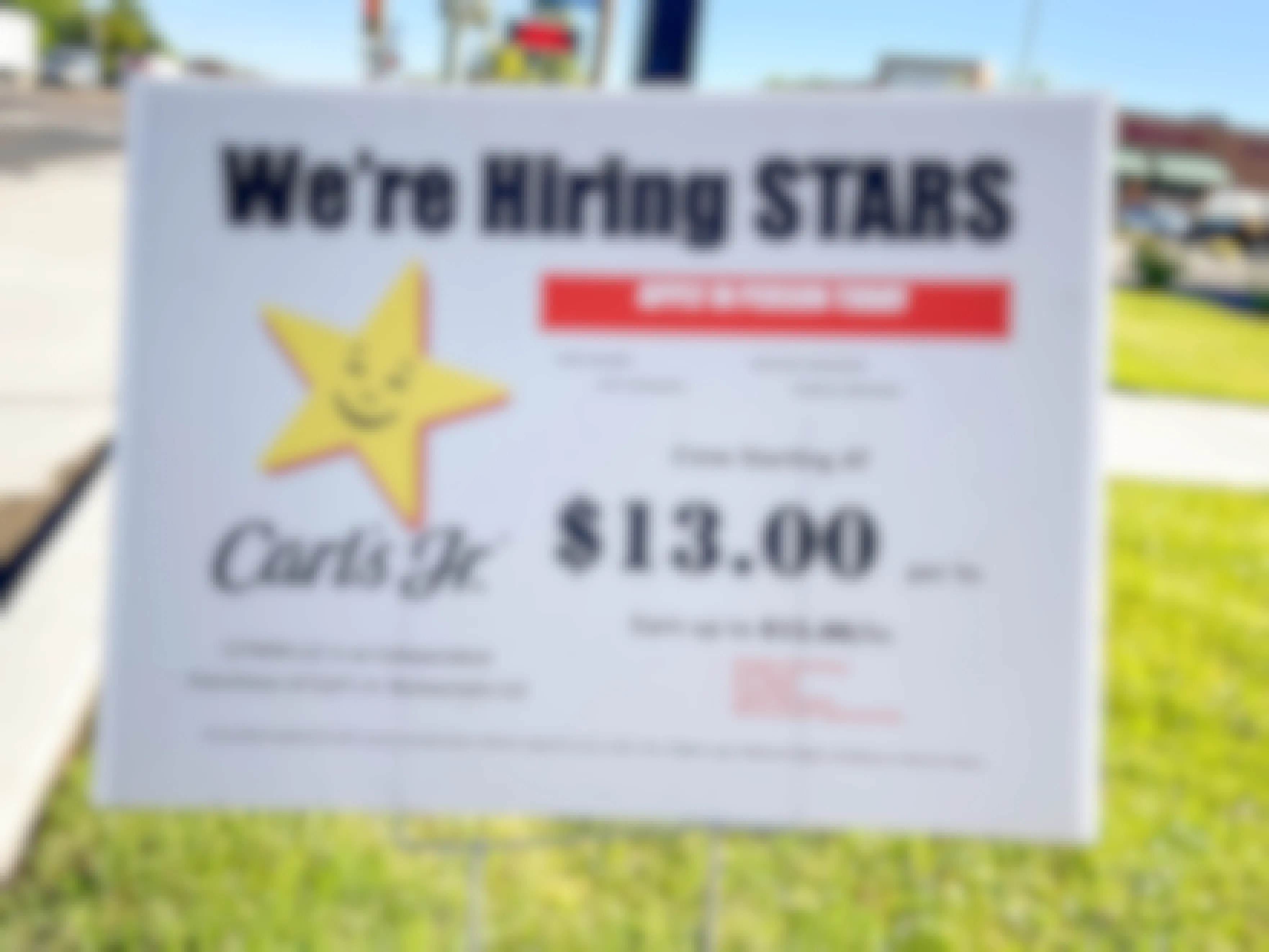 a carls gr hiring sign in the grass outside carls jr