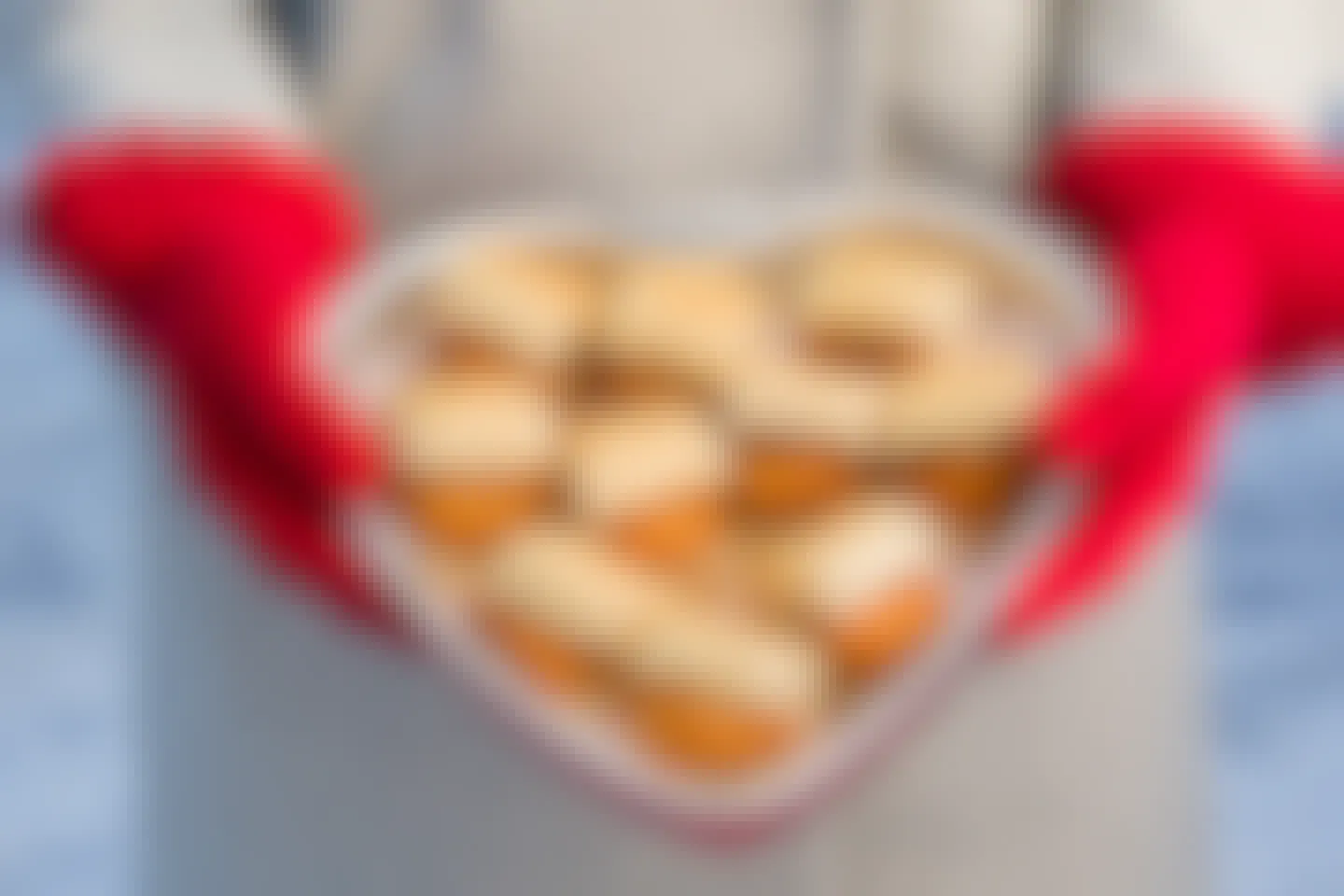 Person with mittens on holding a heart shaped tray of chicken biscuits from Chick-Fil-A