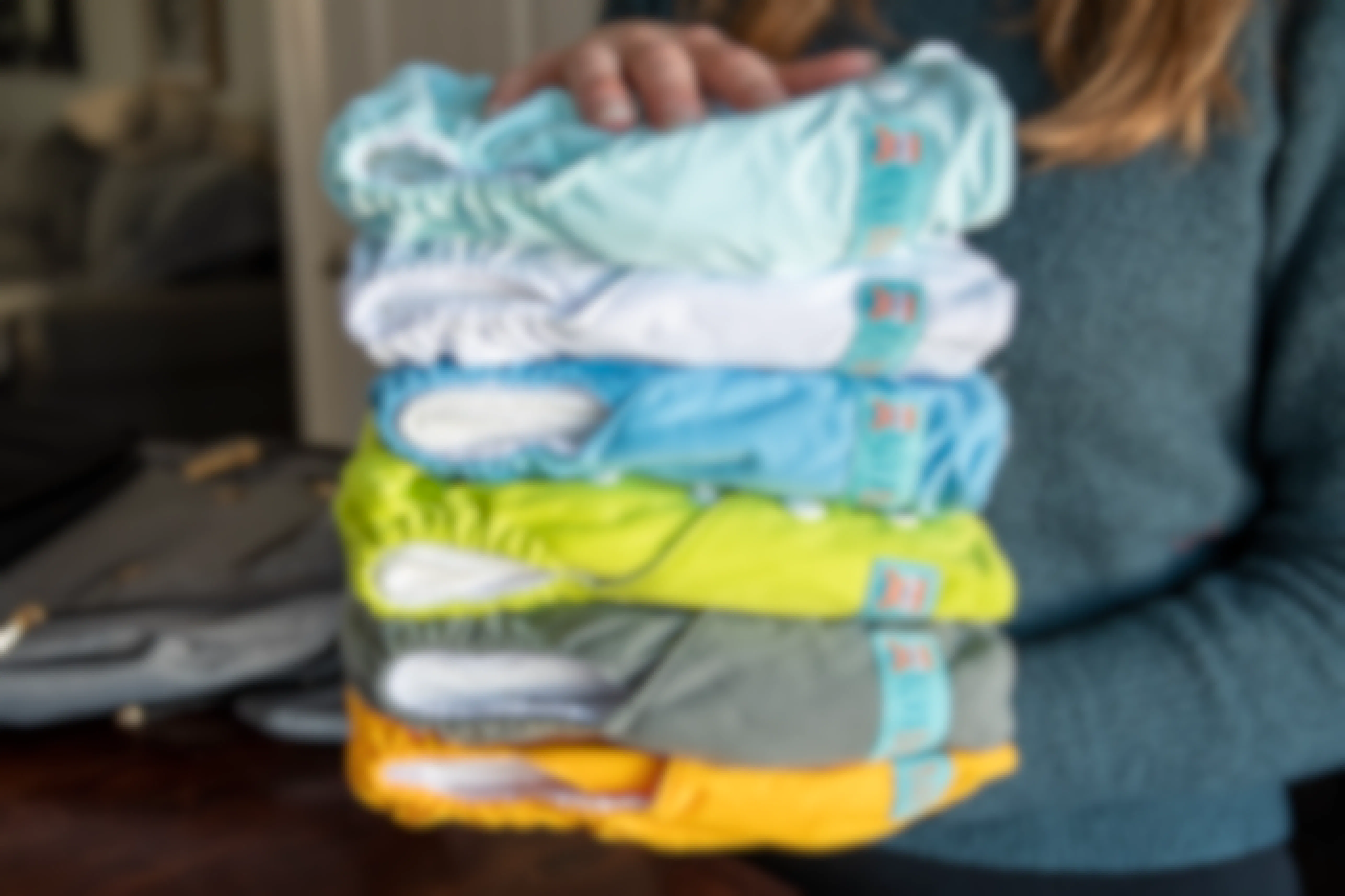 woman holding stack of colorful cloth diapers