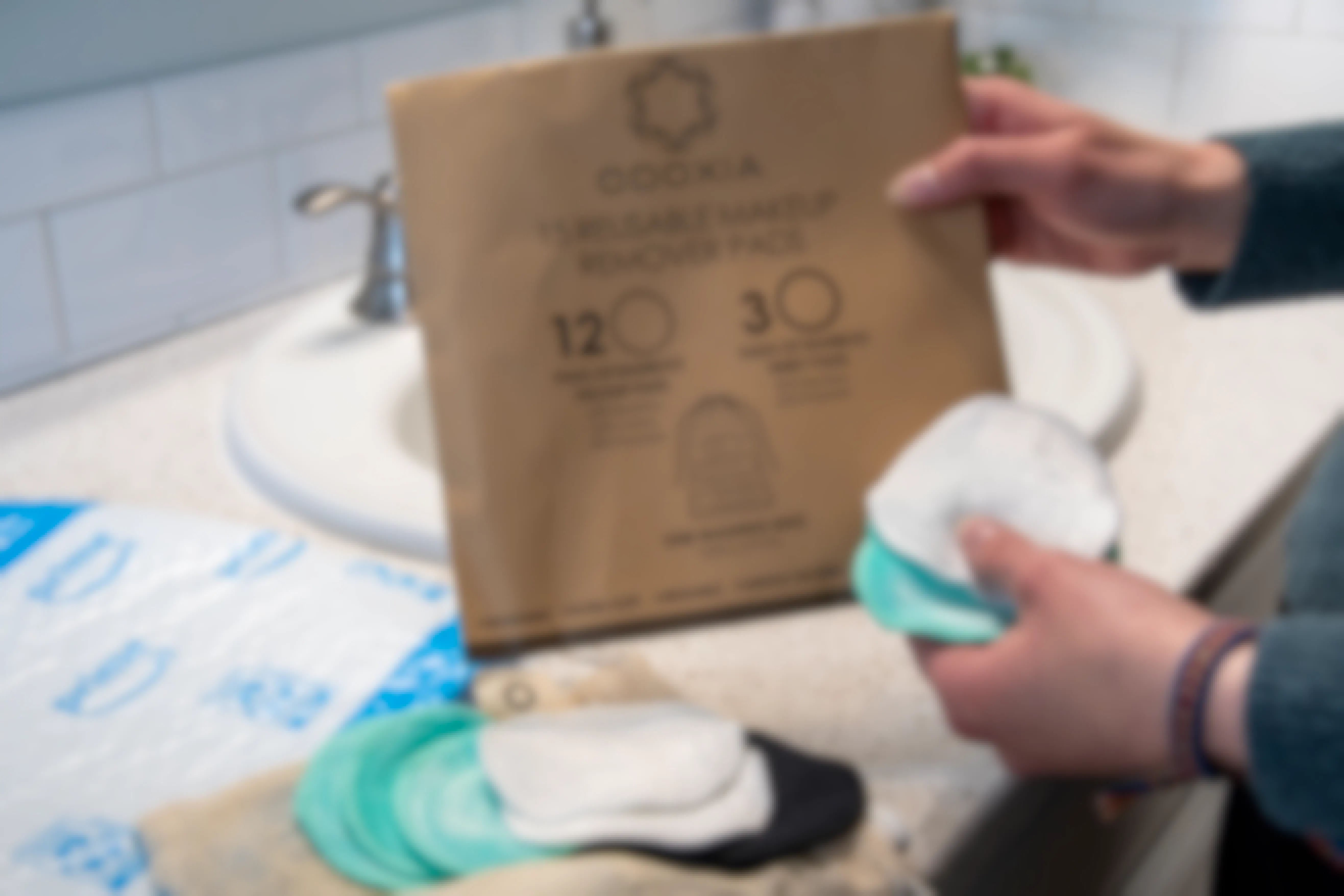 a woman removing reusable makeup remover pads from a package on a bathroom counter