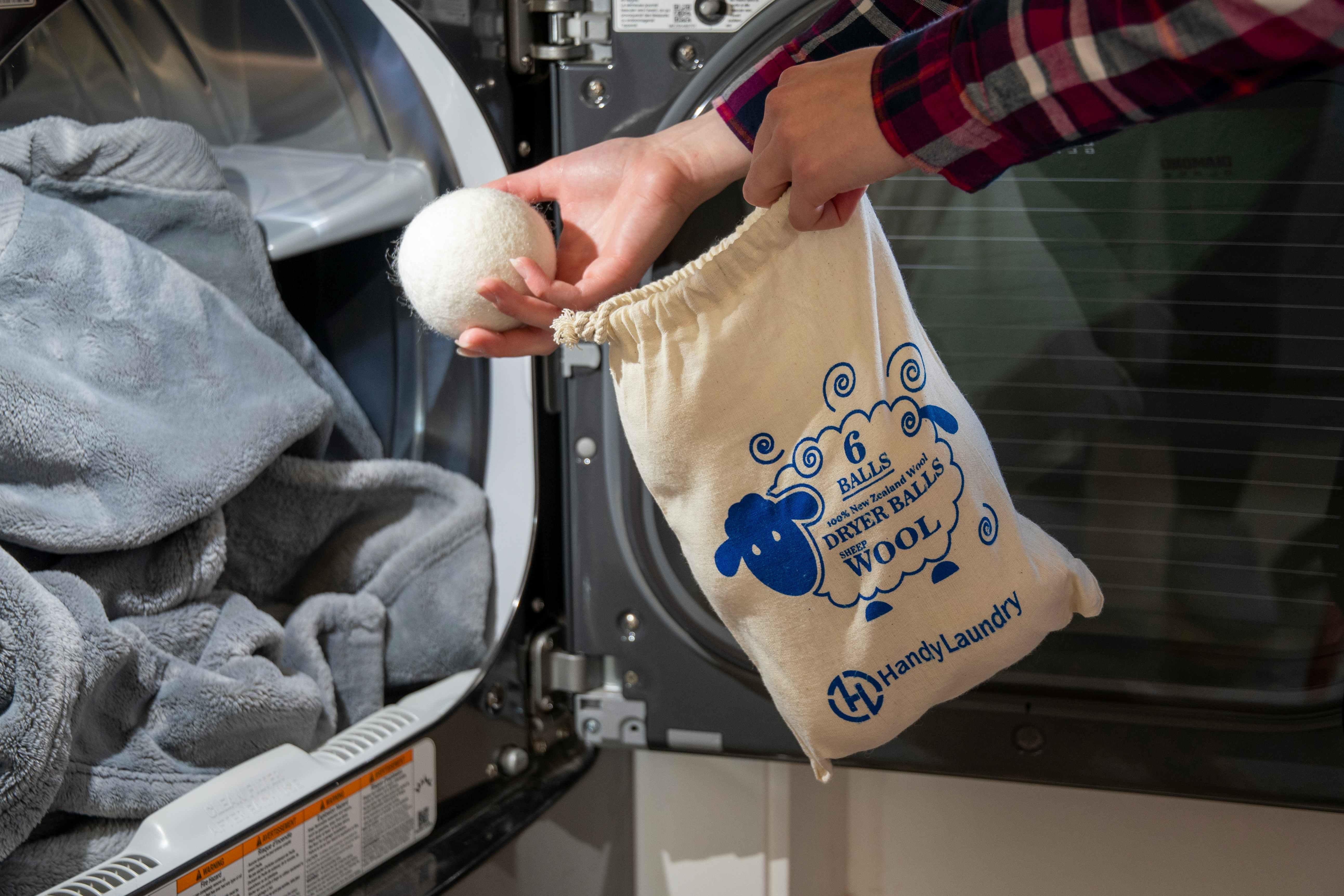 person adding wool dryer balls to laundry in machine