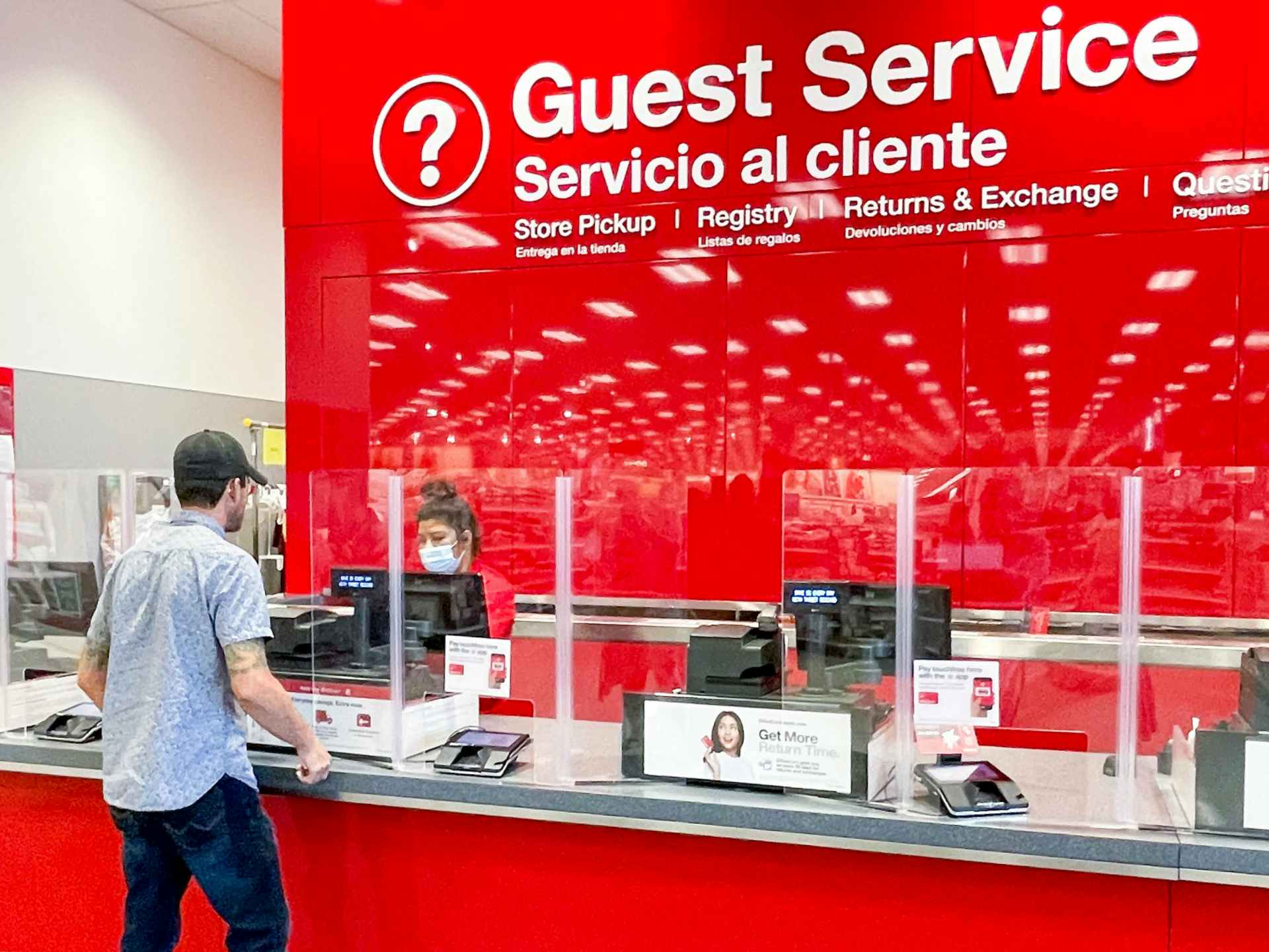 A man talking to an employee at the Target guest service counter.