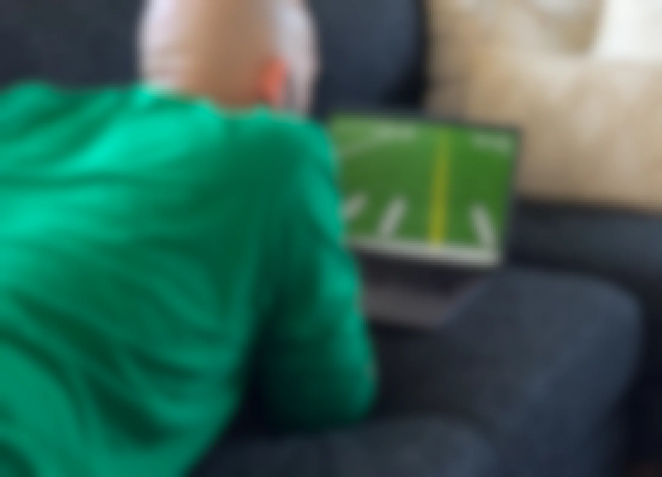 A man laying on a couch watching football on a laptop.