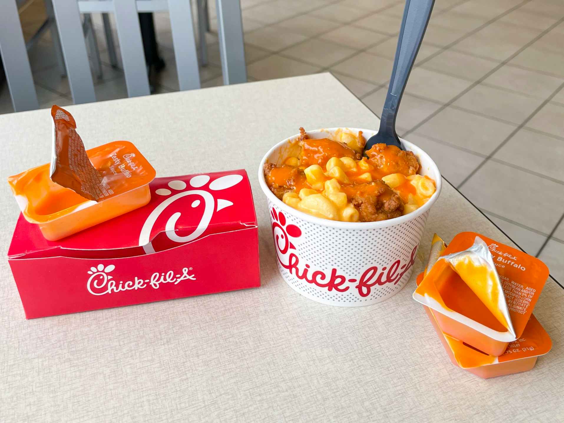 A Buffalo chicken macaroni and cheese secret menu item sitting on a table inside chick-fil-a.