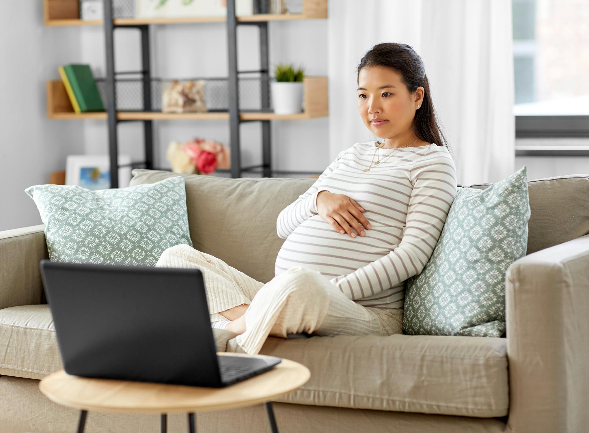 pregnant woman on sofa looking at laptop
