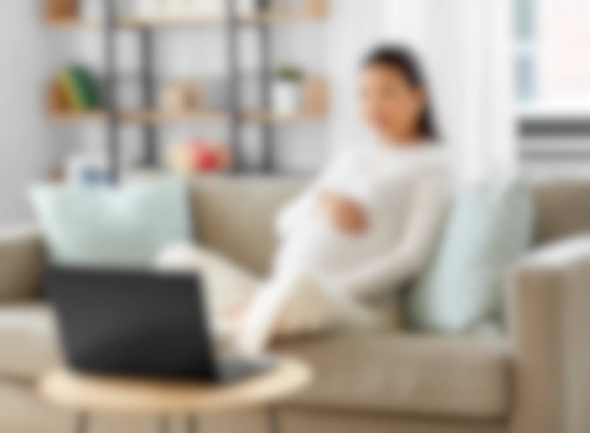 pregnant woman on sofa looking at laptop